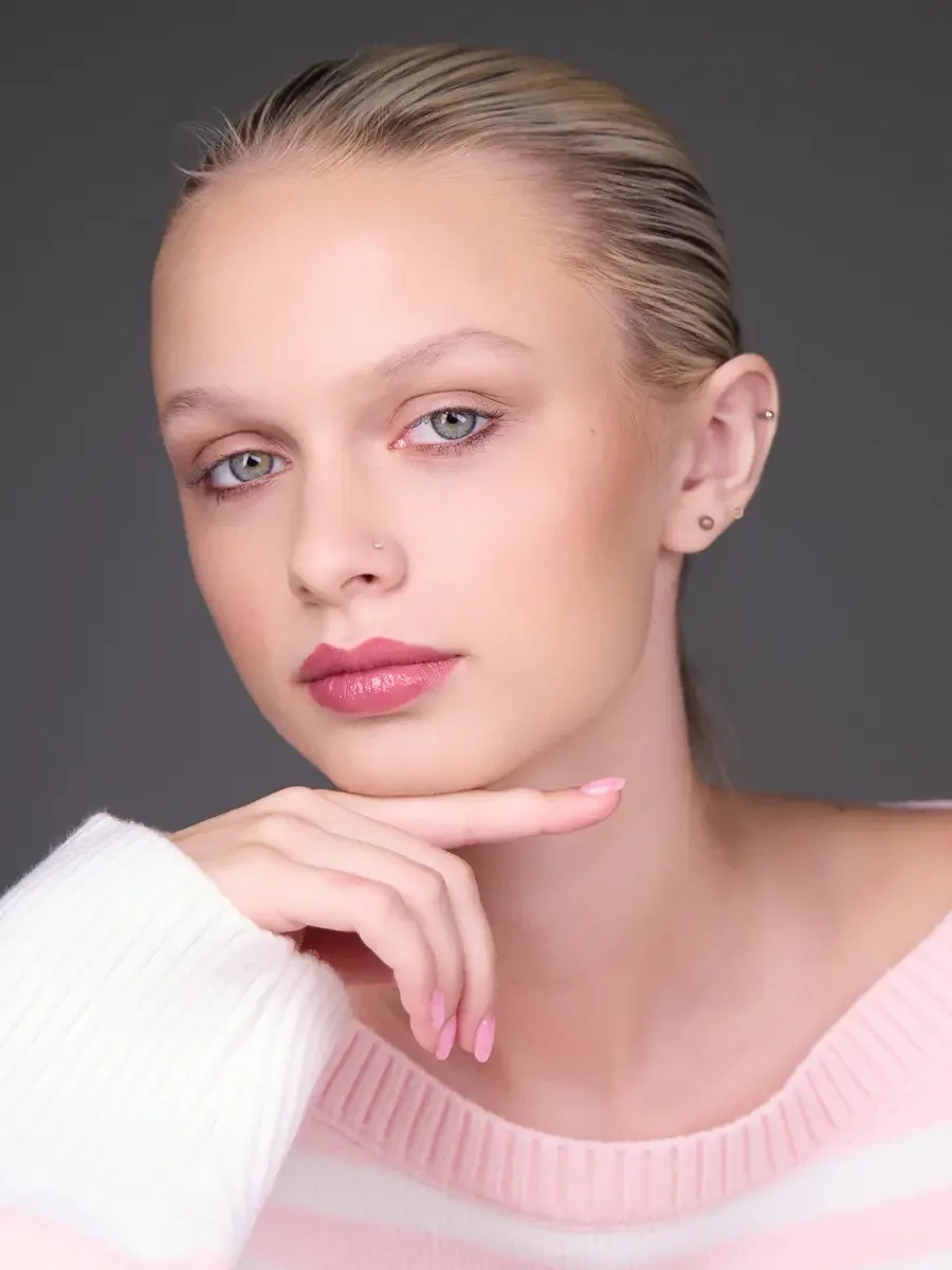 Model portfolio development session, beauty, close-crop, hair slicked back, slight turn, gaze directed left, hand at chin, rose lip, soft eye, pink striped sweater, gray background, photographed by Scott Parker Photo, New York