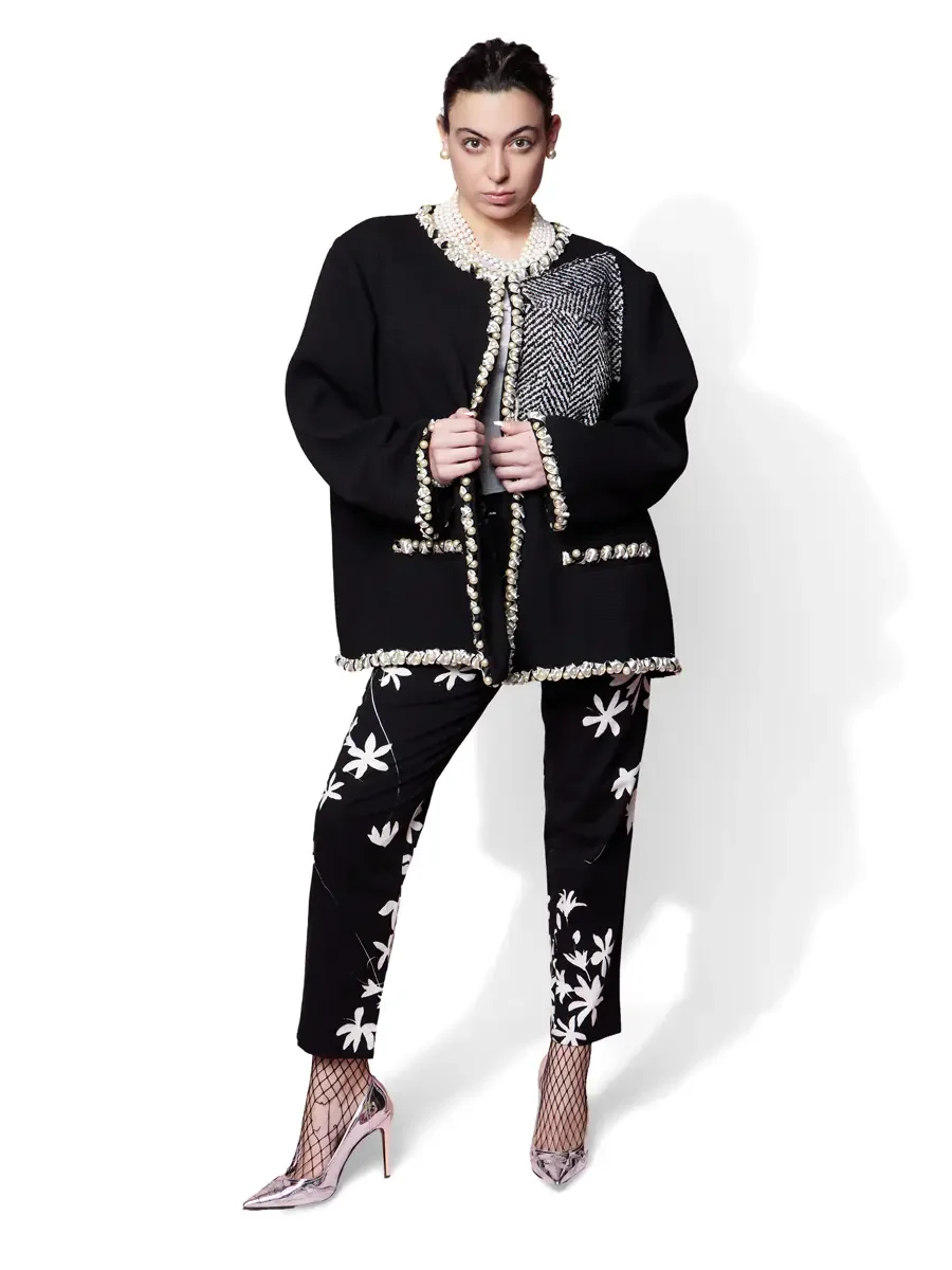 JUS10H 2025 Billboard Magazine UAE feature, model in oversized black jacket with pearl and metallic trim and herringbone patchwork panel over black floral-appliqué trousers, white background, photographed by Scott Parker Photo