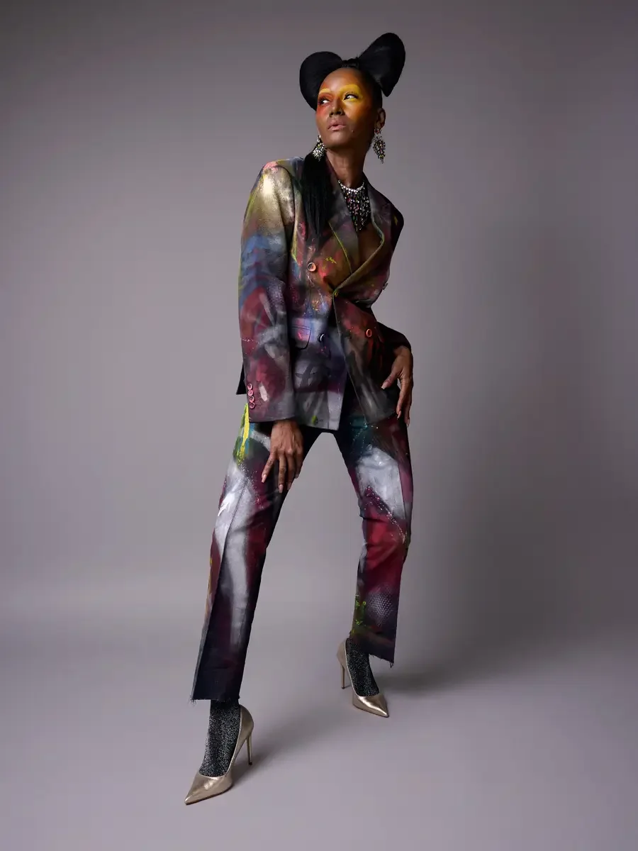 JUS10H Met Monday 2026, full-length hand-painted suit, looking upward, iridescent necklace and earrings, grey background, photographed by Scott Parker Photo
