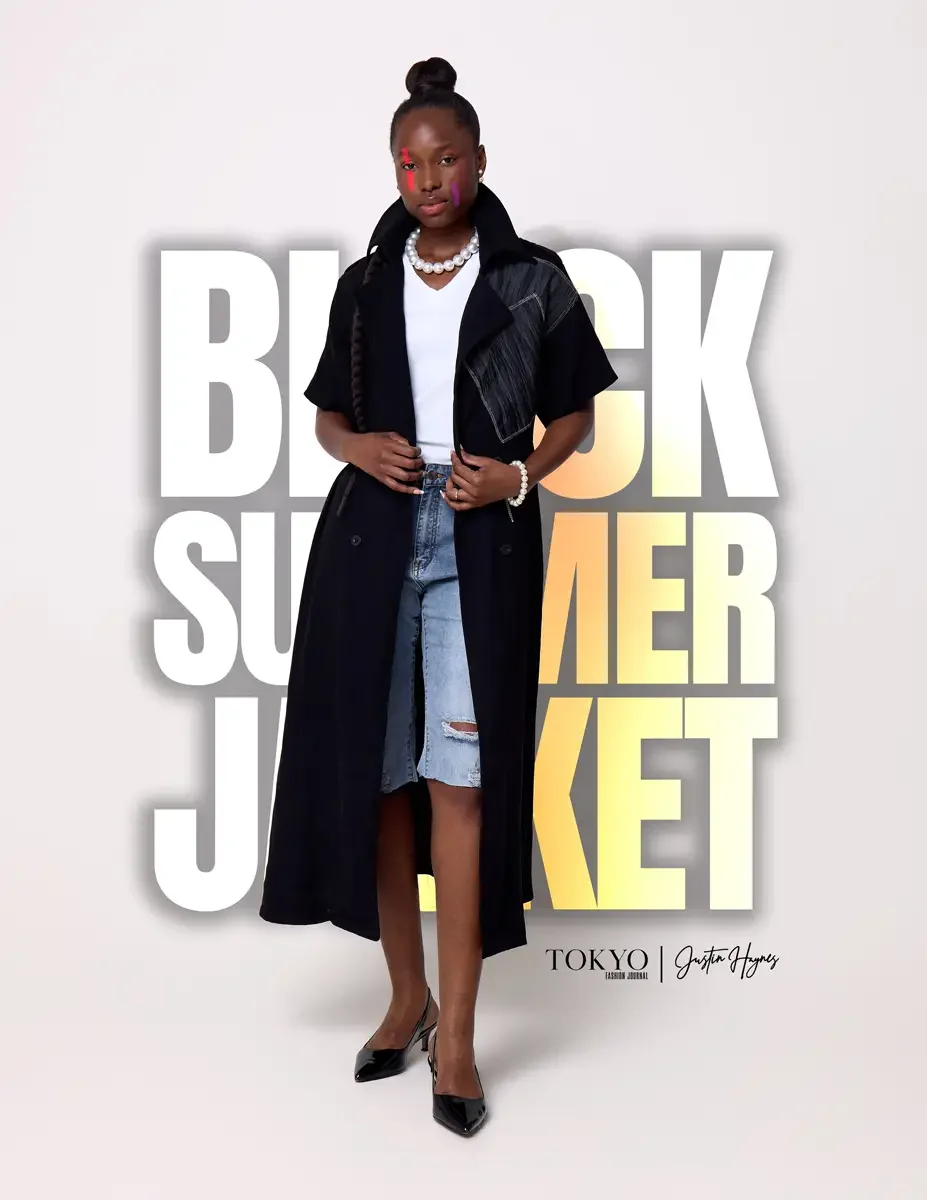 JUS10H Black Summer Jacket lookbook, female model in black long-line double-breasted jacket with gray patchwork shoulder panel worn open over white tee, distressed denim shorts, pearl necklace, black slingback heels, white background, photographed by