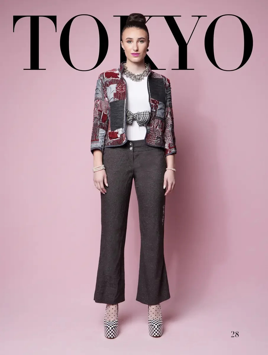 JUS10H 2025 Tokyo lookbook, red and grey multi-pattern patchwork jacket with houndstooth bow belt over white top and dark charcoal wide leg trousers with checkered platform boots, pink background, photographed by Scott Parker Photo for the Tokyo Fash