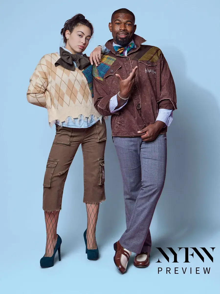 JUS10H 2025 promotional image, two models standing together, female in camel argyle fringe sweater with multicolor tartan patchwork panel, olive bow, and brown cargo capris over fishnet tights, male in brown washed field jacket with multicolor tartan