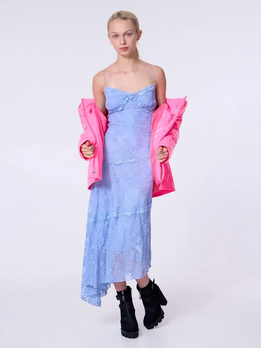 Model portfolio development session, commercial look, hot pink vinyl puffer jacket worn off shoulders over periwinkle blue lace asymmetrical midi dress, full-length, facing camera, jacket held at sides, lace dress bodice and tiered skirt fully on dis