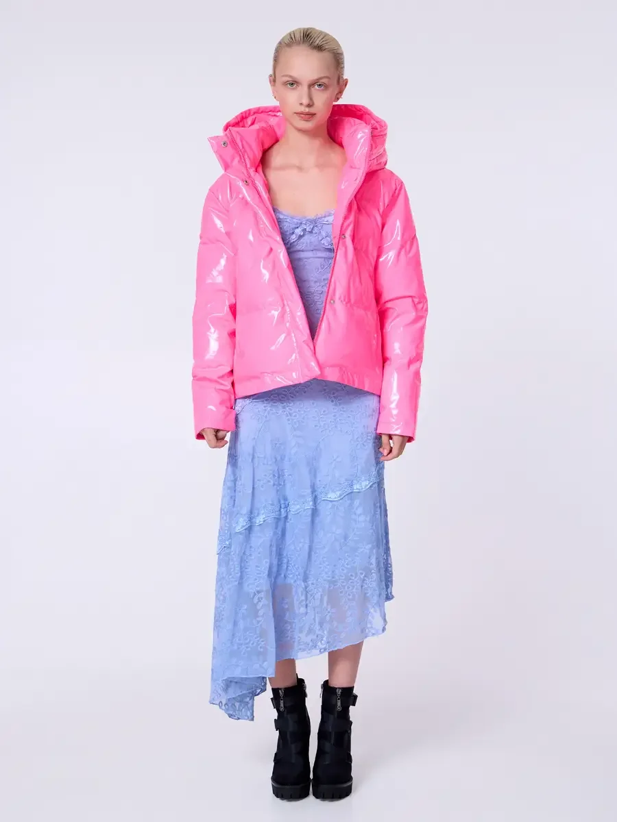 Model portfolio development session, commercial look, hot pink vinyl puffer jacket with hood open over periwinkle blue lace asymmetrical midi dress, full-length, facing camera, arms at sides, direct gaze, glossy vinyl texture of jacket contrasting la