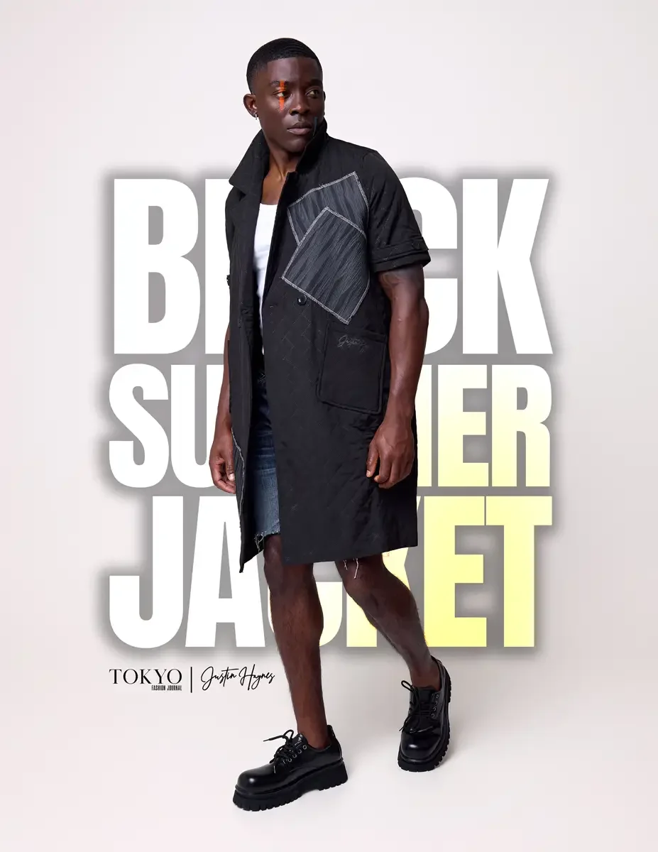 JUS10H Black Summer Jacket lookbook, male model in black long-line short-sleeve jacket with gray patchwork panel worn open, distressed denim shorts, black lace-up boots, white background, photographed by Scott Parker Photo