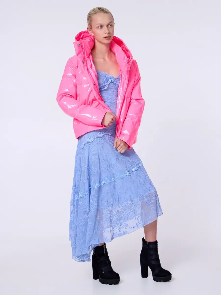 Model portfolio development session, commercial look, hot pink vinyl puffer jacket with hood over periwinkle blue lace asymmetrical midi dress, full-length, three-quarter turn, hands at jacket hem, gaze directed off-camera, high-heel black lug-sole a