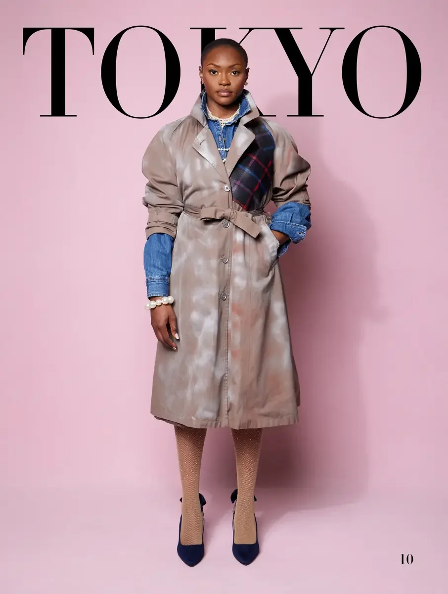 JUS10H 2025 Tokyo lookbook, tie-dye taupe trench coat with tartan patch over denim shirt and pearl bracelet, pink background, photographed by Scott Parker Photo for the Tokyo Fashion Council
