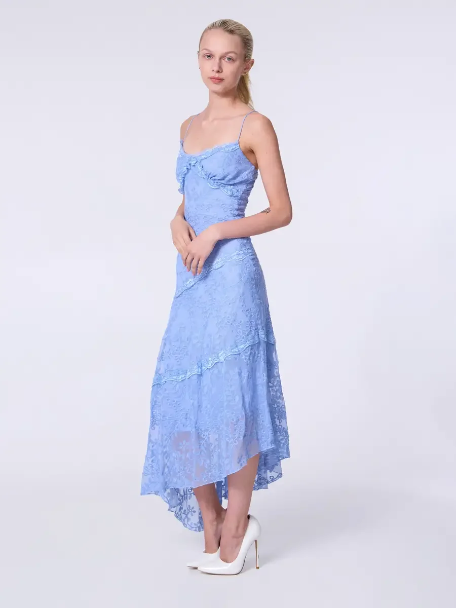Model portfolio development session, commercial look, periwinkle blue lace asymmetrical midi dress with ruffle bodice detail and spaghetti straps, full-length, three-quarter turn, hands loosely clasped at waist, diagonal lace tier seams and asymmetri