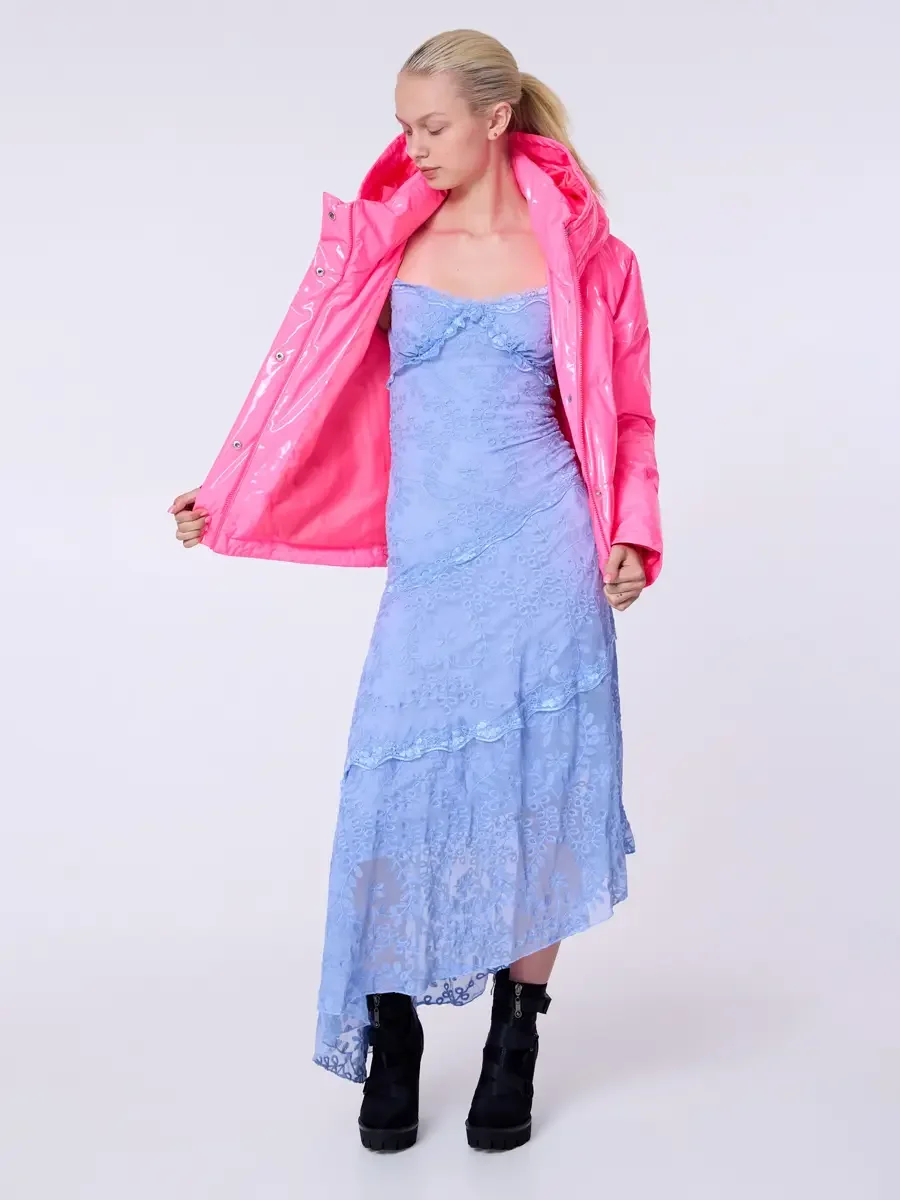 Model portfolio development session, commercial look, hot pink vinyl puffer jacket held open over periwinkle blue lace asymmetrical midi dress, full-length, slight turn, gaze downward, one hand pulling jacket lapel open to reveal full lace dress bodi