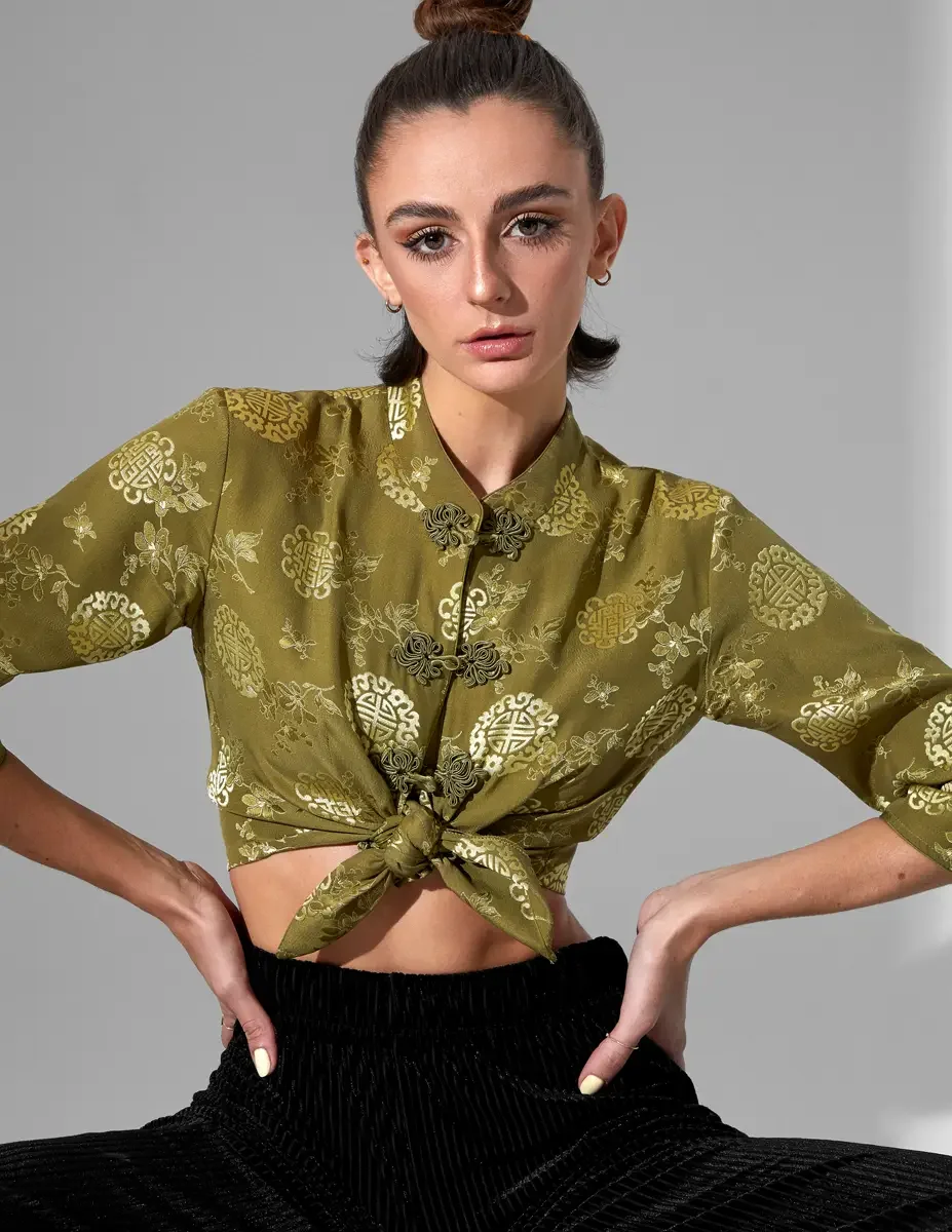 Macy, hip crop, seated, hands on hips, olive green satin jacquard tied crop top with gold medallion print, mandarin collar and frog closures visible, black wide-leg ribbed velvet culottes, New York studio test shoot, photographed by Scott Parker Phot