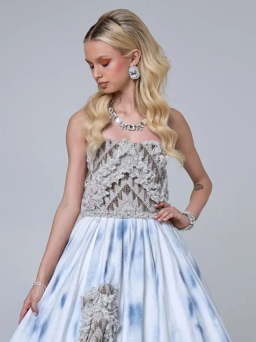 JUS10H 2025 New York Bridal Fashion Week, detail of ice-blue tie-dye ball gown with strapless dimensional lace bodice and lace patch appliqué on the skirt, styled with a crystal statement necklace, oversized crystal earrings, and stacked crystal brac