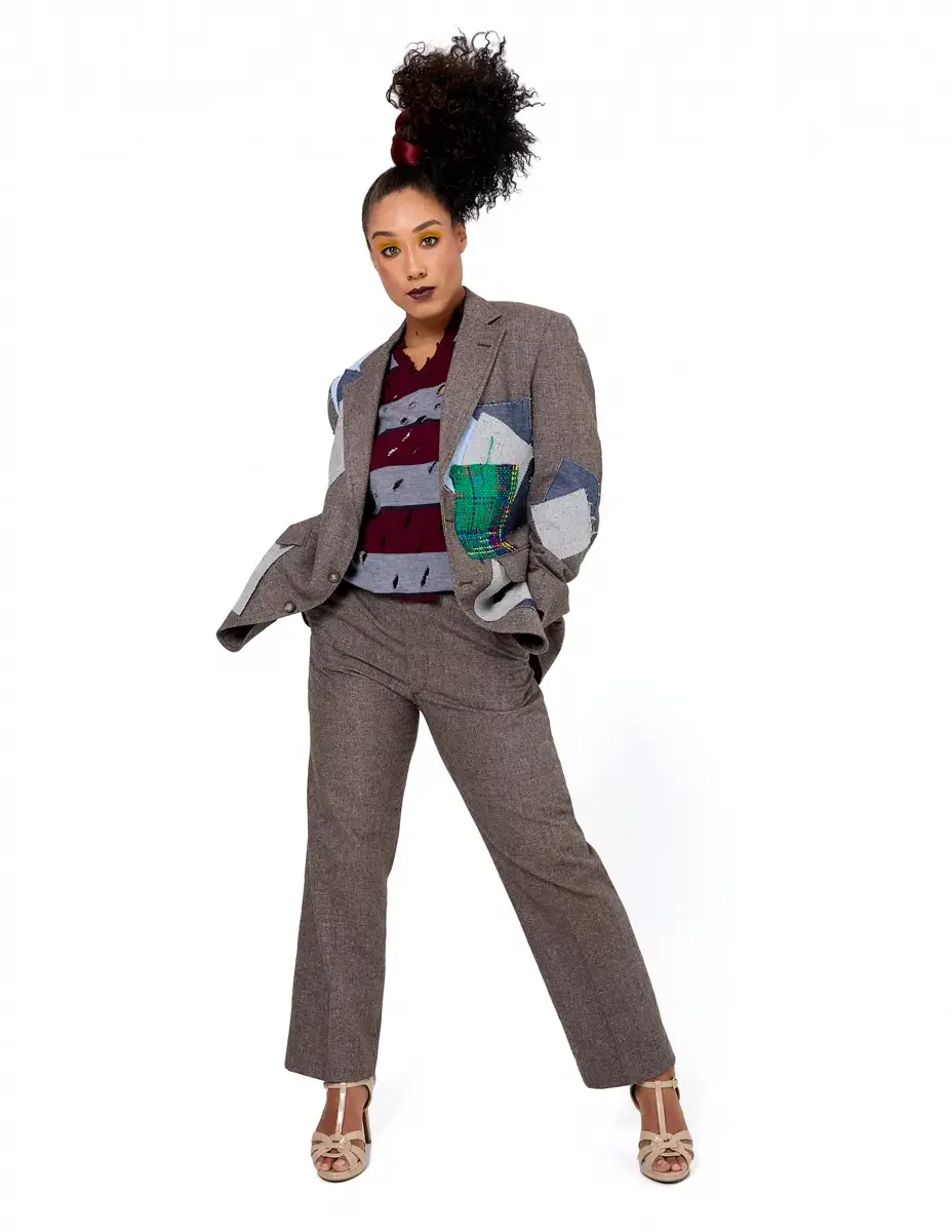 Model portfolio development session, high fashion editorial look, oversized heathered blazer with mixed fabric appliqué panels over burgundy and heather grey destroyed-knit stripe sweater with raw-edge sleeves, straight-leg heathered trousers, nude t