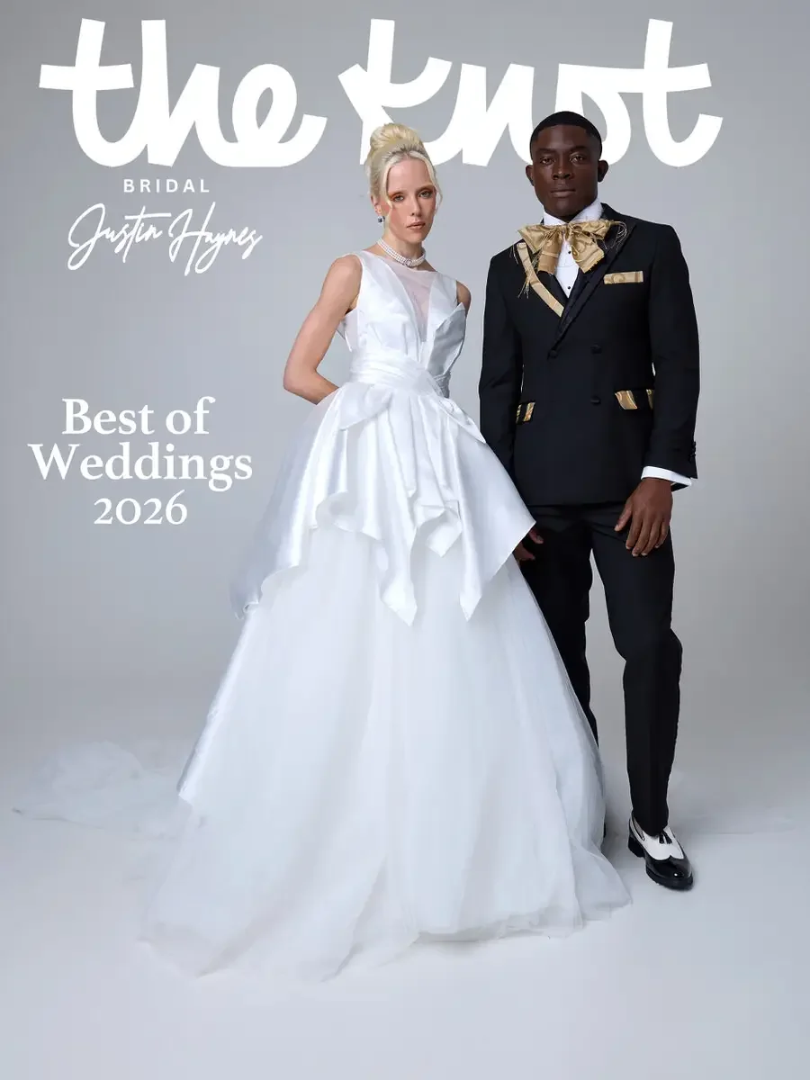 JUS10H 2025 The Knot Bridal feature, Justin Haynes Best of Weddings 2026 cover, white sculptural ball gown with deep-V illusion neckline and draped skirt alongside black double-breasted suit with gold bow tie and pocket square, photographed by Scott 