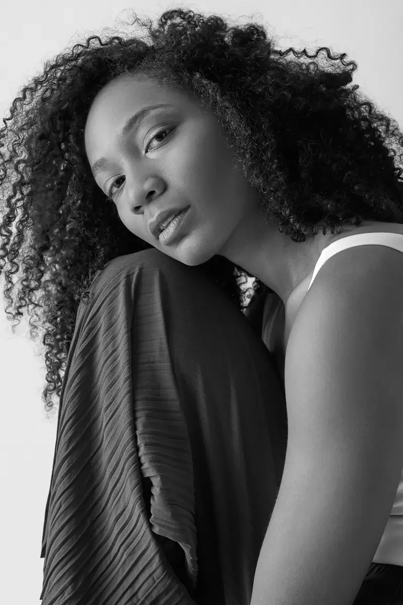 Arielle Chambers, profile, white tank and burgundy wide-leg pleated pants, studio stool, East Williamsburg studio test shoot, makeup by Schanica Pickens, photographed by Scott Parker Photo