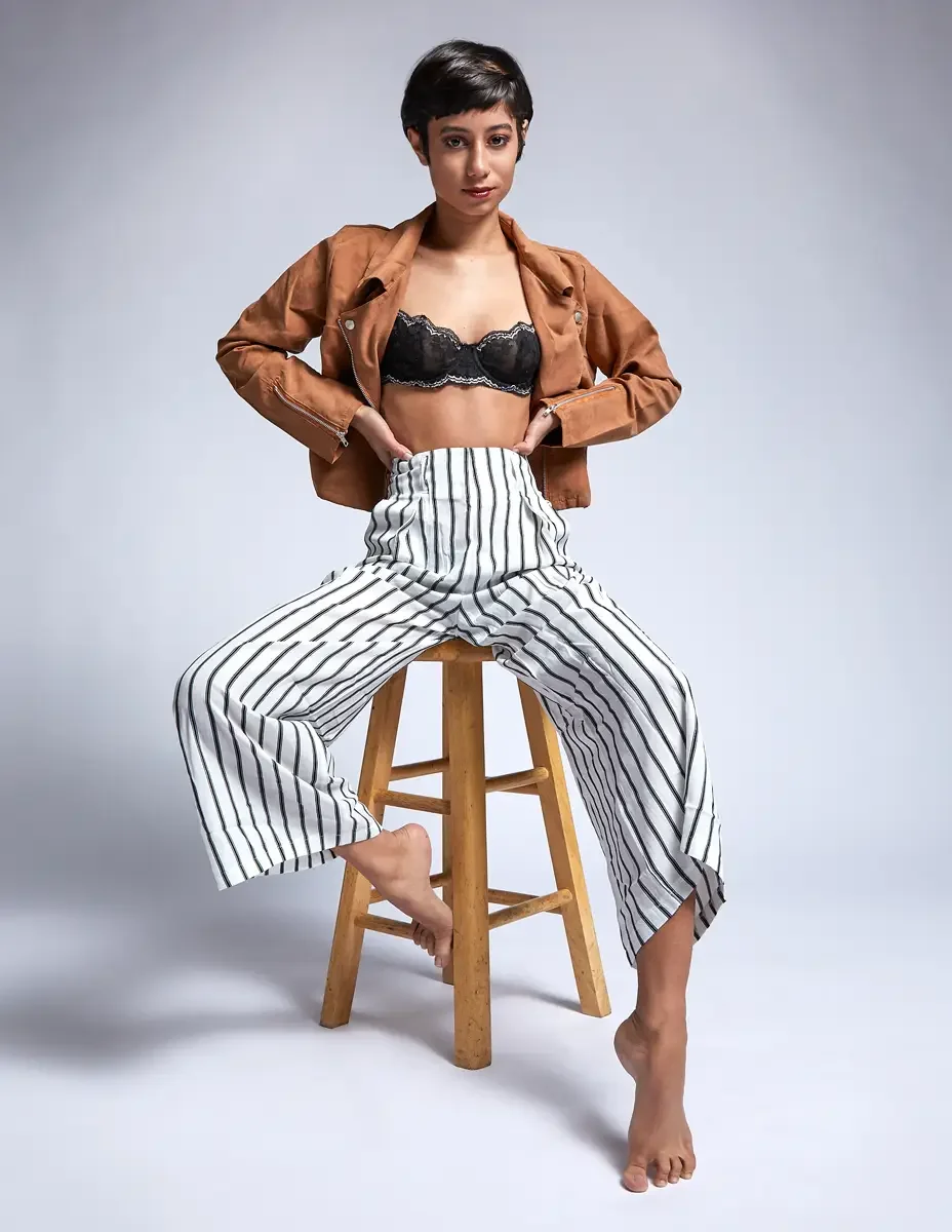 Eloissa, seated, black lace bralette and striped high-waisted wide-leg trousers, floral forearm tattoo, studio stool, East Williamsburg studio test shoot, makeup by Schanica Pickens, photographed by Scott Parker Photo