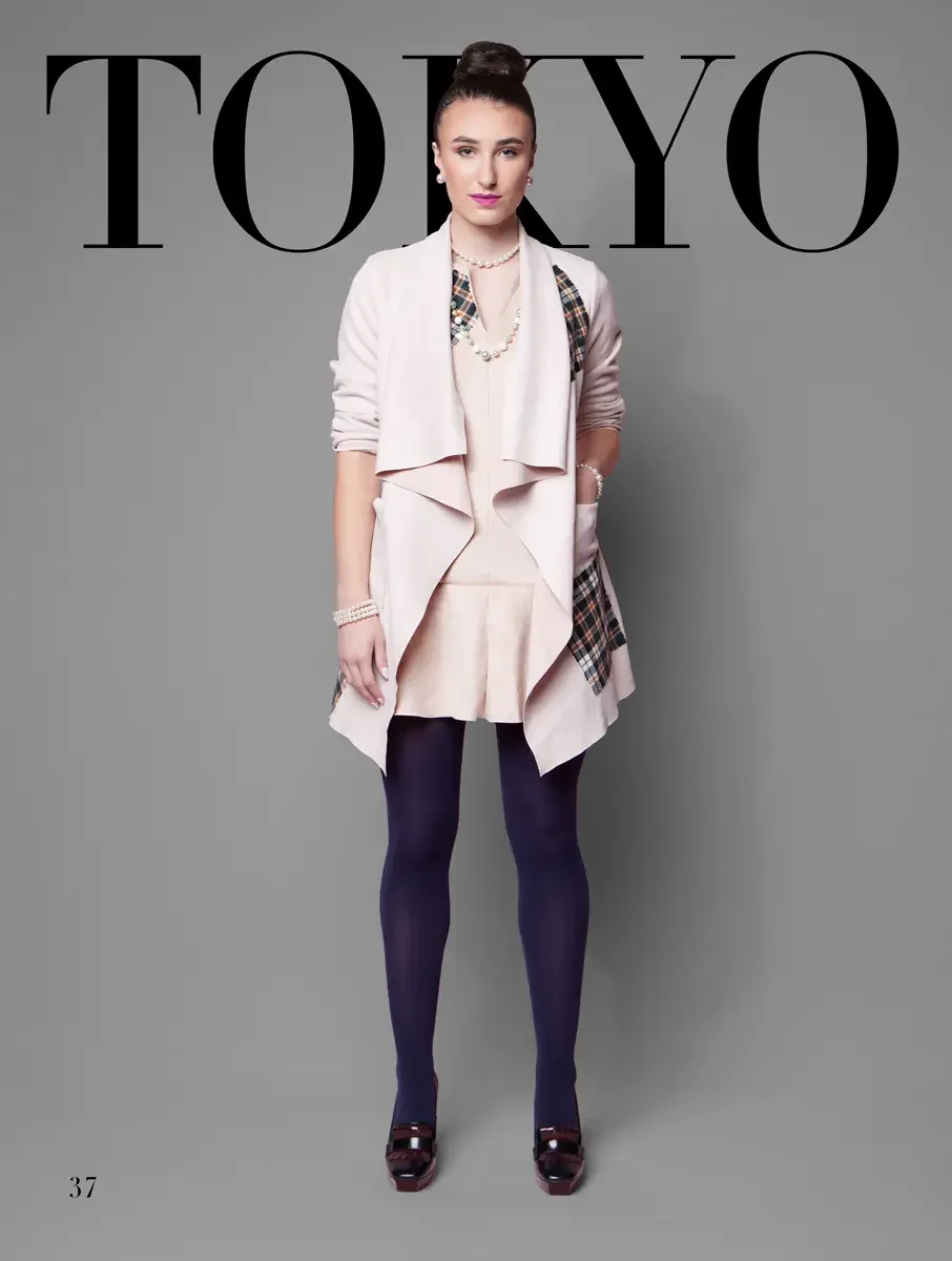 JUS10H 2025 Tokyo lookbook, a model wearing a blush pink long waterfall-lapel cardigan coat over a blush pink peplum dress with a plaid panel detail at the sides, styled with layered pearl necklaces, a pearl bracelet, navy tights, and dark burgundy p