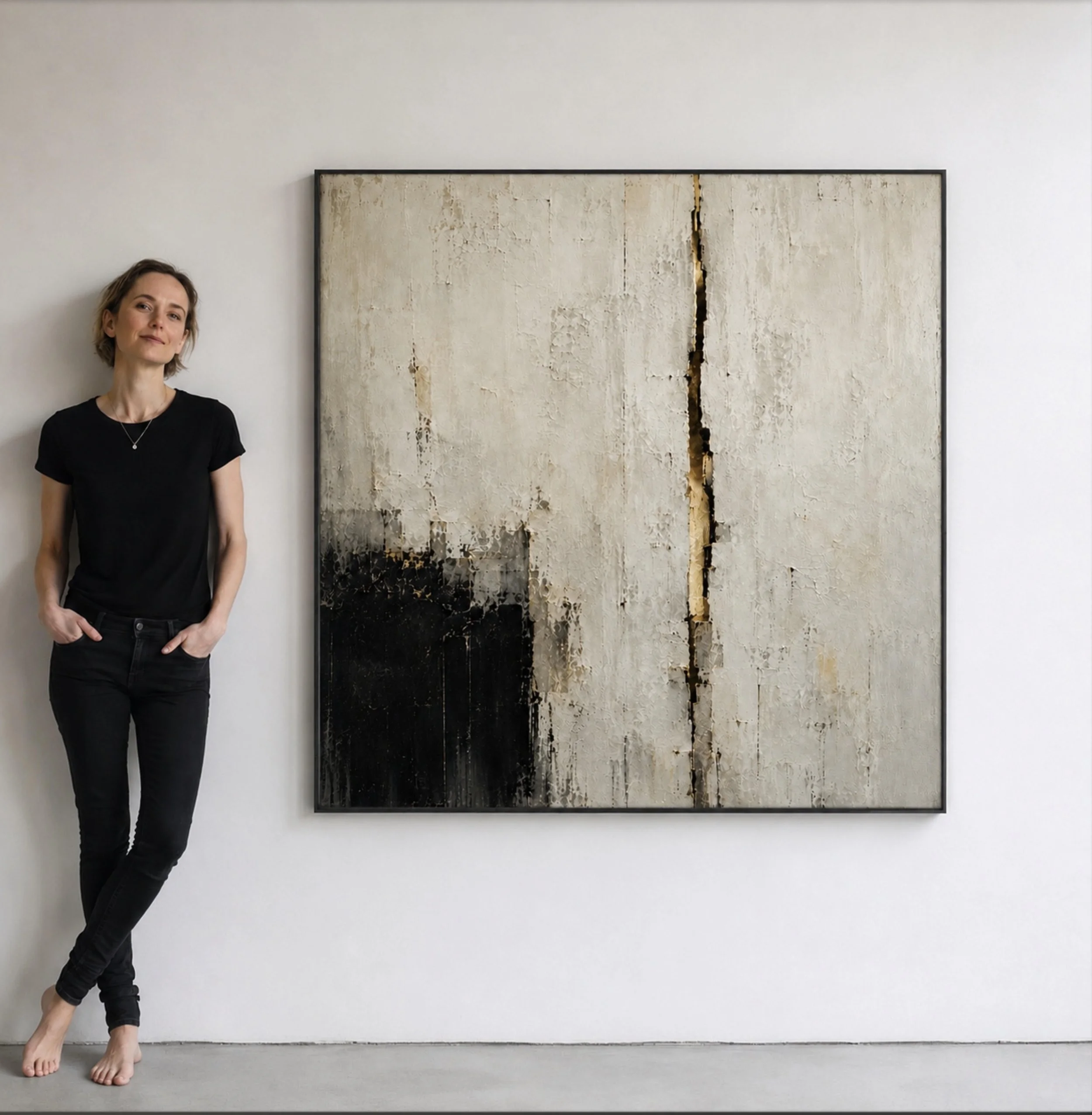 A woman with short hair in a black shirt and pants standing barefoot in front of an abstract artwork on a white wall.