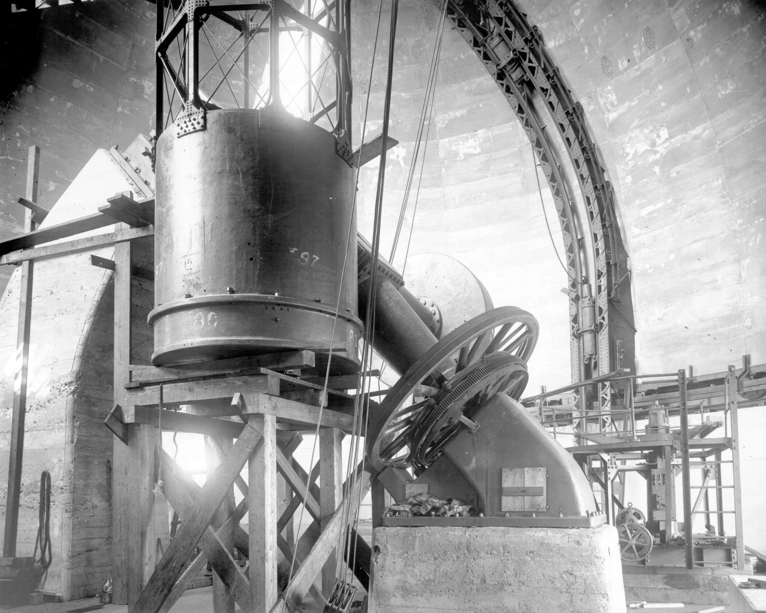 A large industrial slide or chute surrounded by wooden scaffolding inside a concrete structure, possibly part of a construction or manufacturing site.