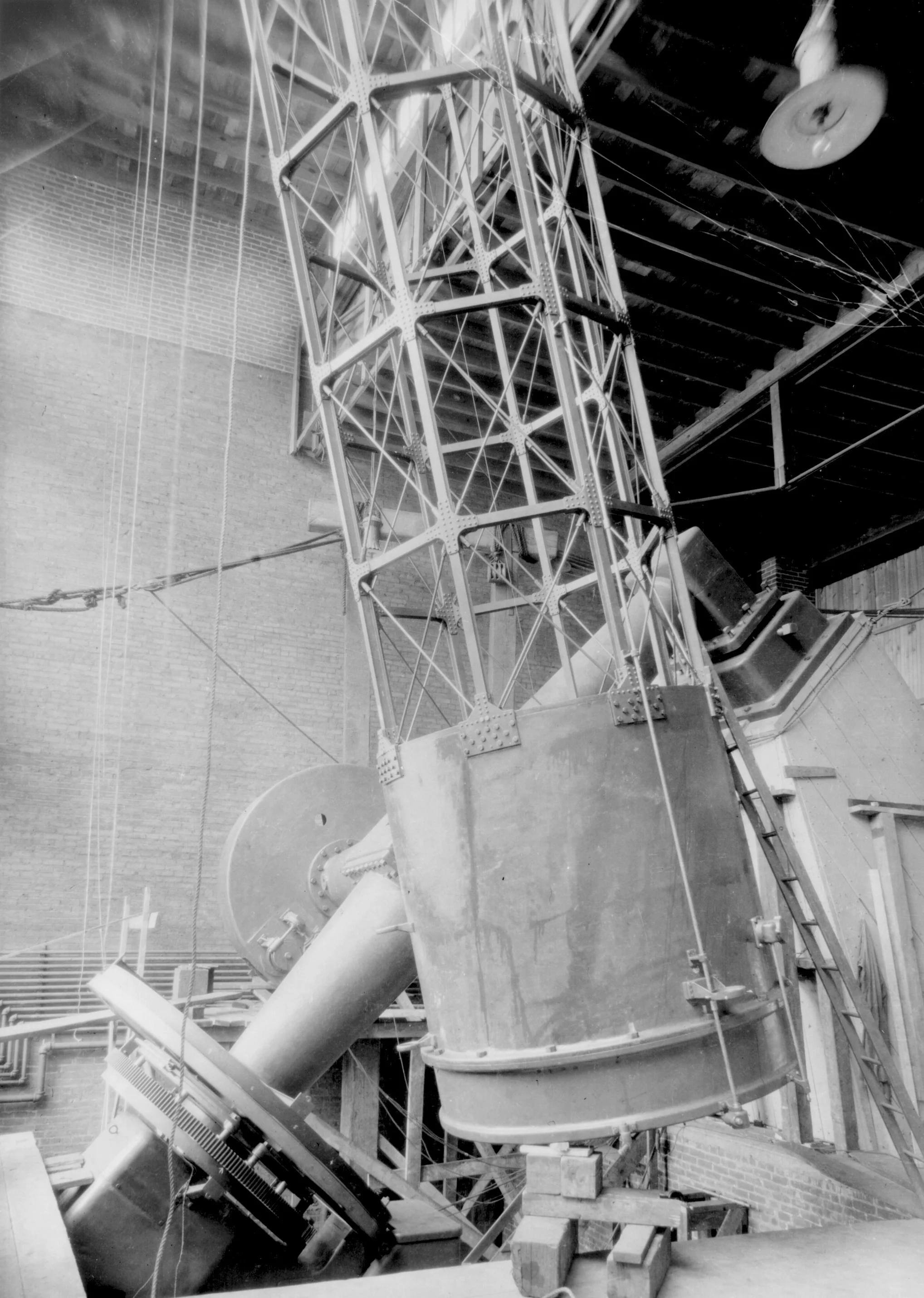 Vintage large telescope inside an observatory with a metal framework and ladder.