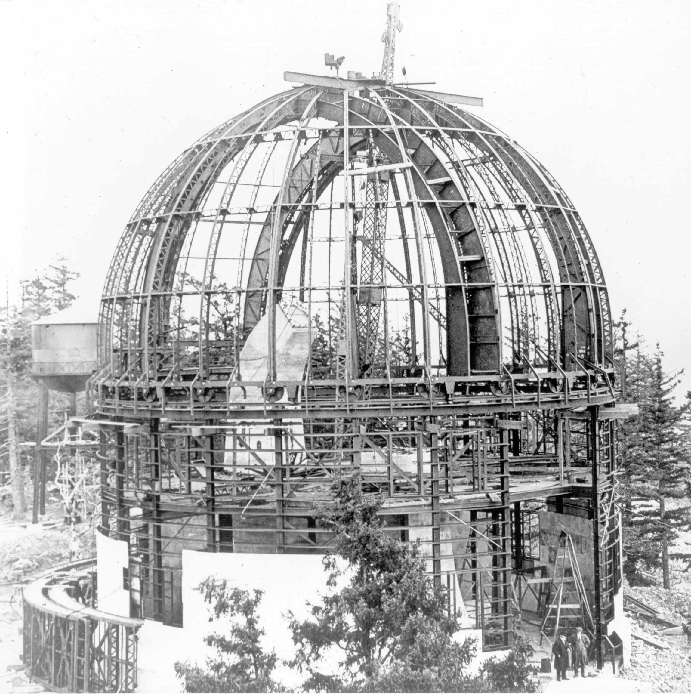 Black and white photo of a large dome structure under construction with visible steel framework.
