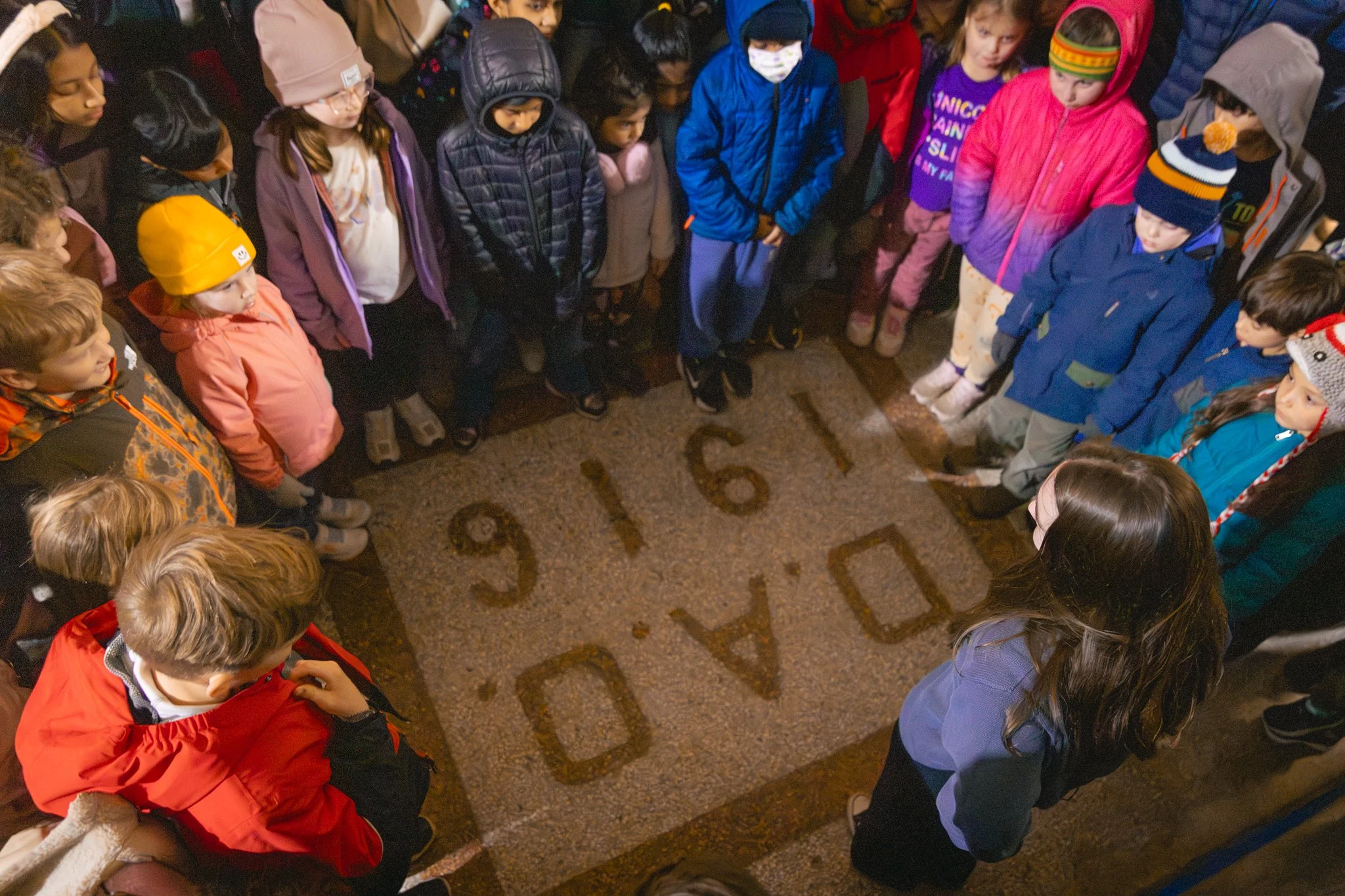 Children standing in a circle on a floor with the word 'STORY' written around the edges.