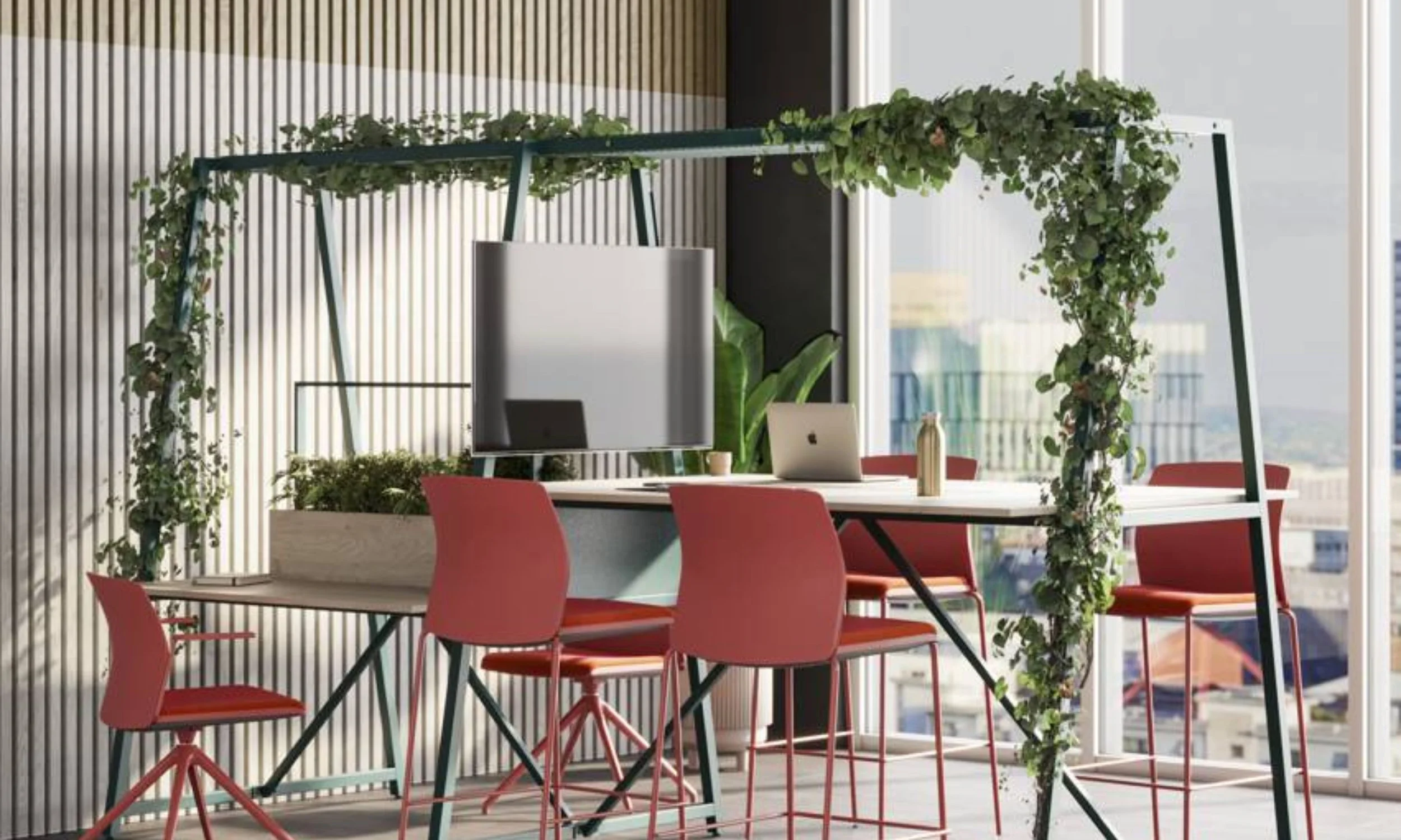 Modern office workspace with red chairs around a white table, decorated with greenery and set near large windows in a high-rise building.