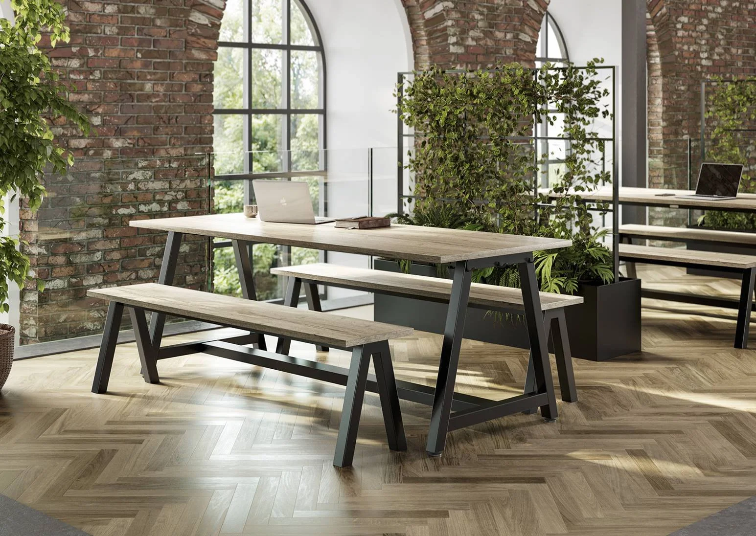 Modern office space with wooden table, benches, and plants, large arched windows, brick walls, and wooden flooring.