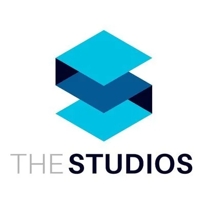 A logo with three stacked blue and cyan rectangles creating a three-dimensional effect above the text 'THE STUDIOS' in gray and black.
