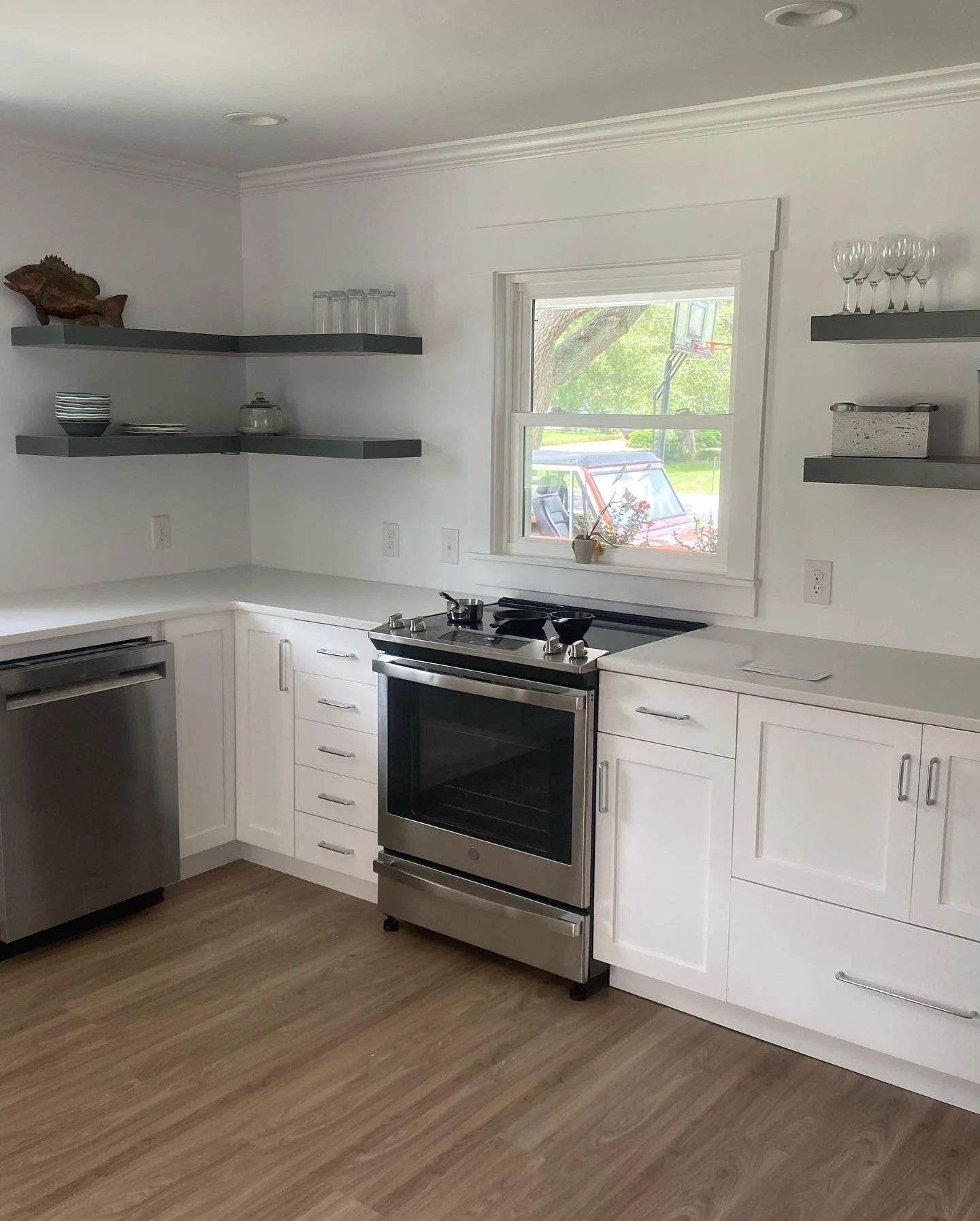 A modern kitchen with custom white cabinets and floating shelves.