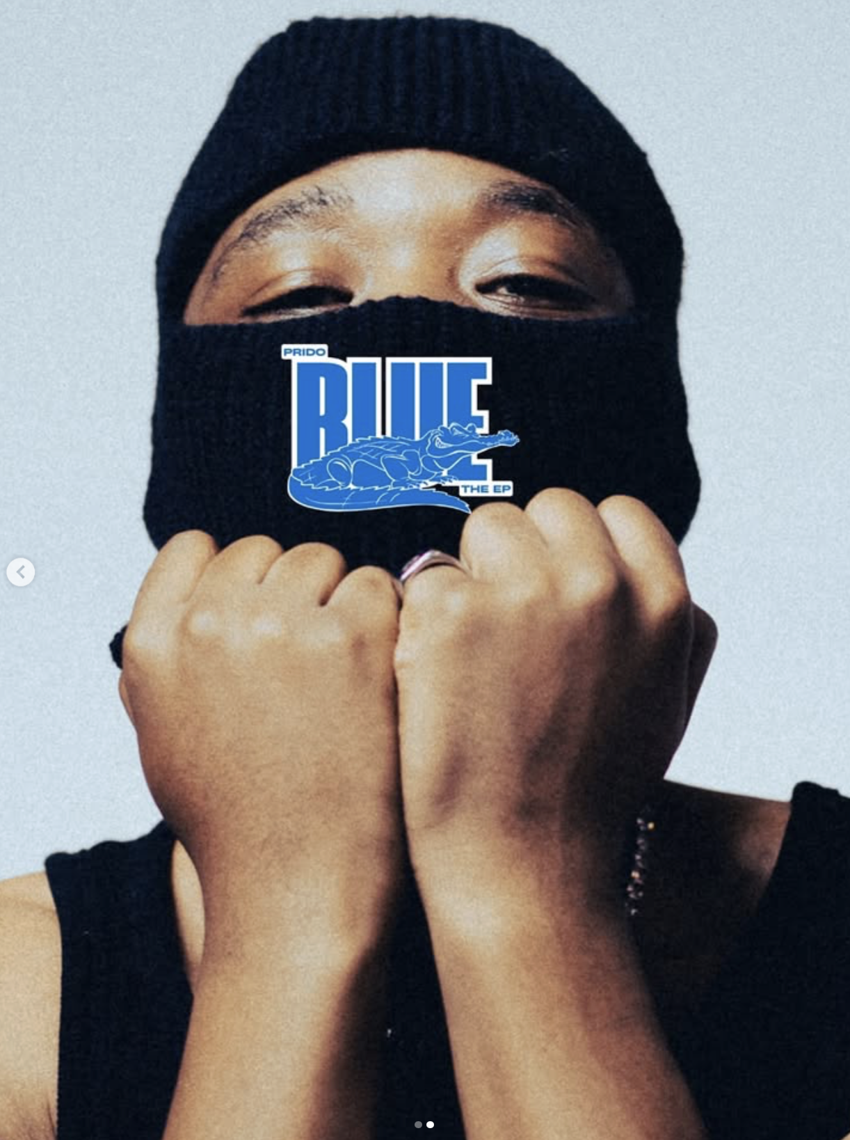 Person wearing a black beanie and face mask, covering their face and a sticker with a blue crocodile and the words 'PRIDO BLUE THE EP' on the mask. Open-plan photography and videography studio at The Space MCR in North Manchester.