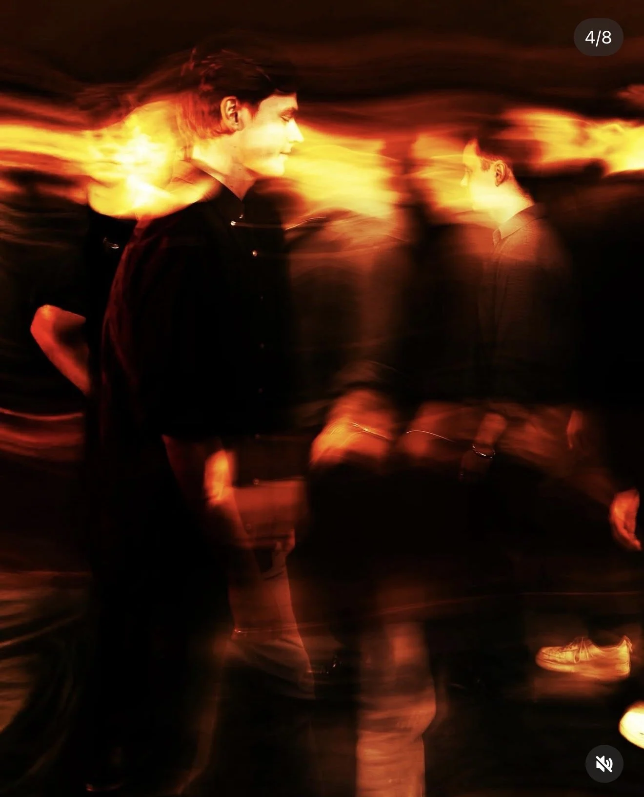 Two men walking in front of a fiery, blurred background with a warm color palette.