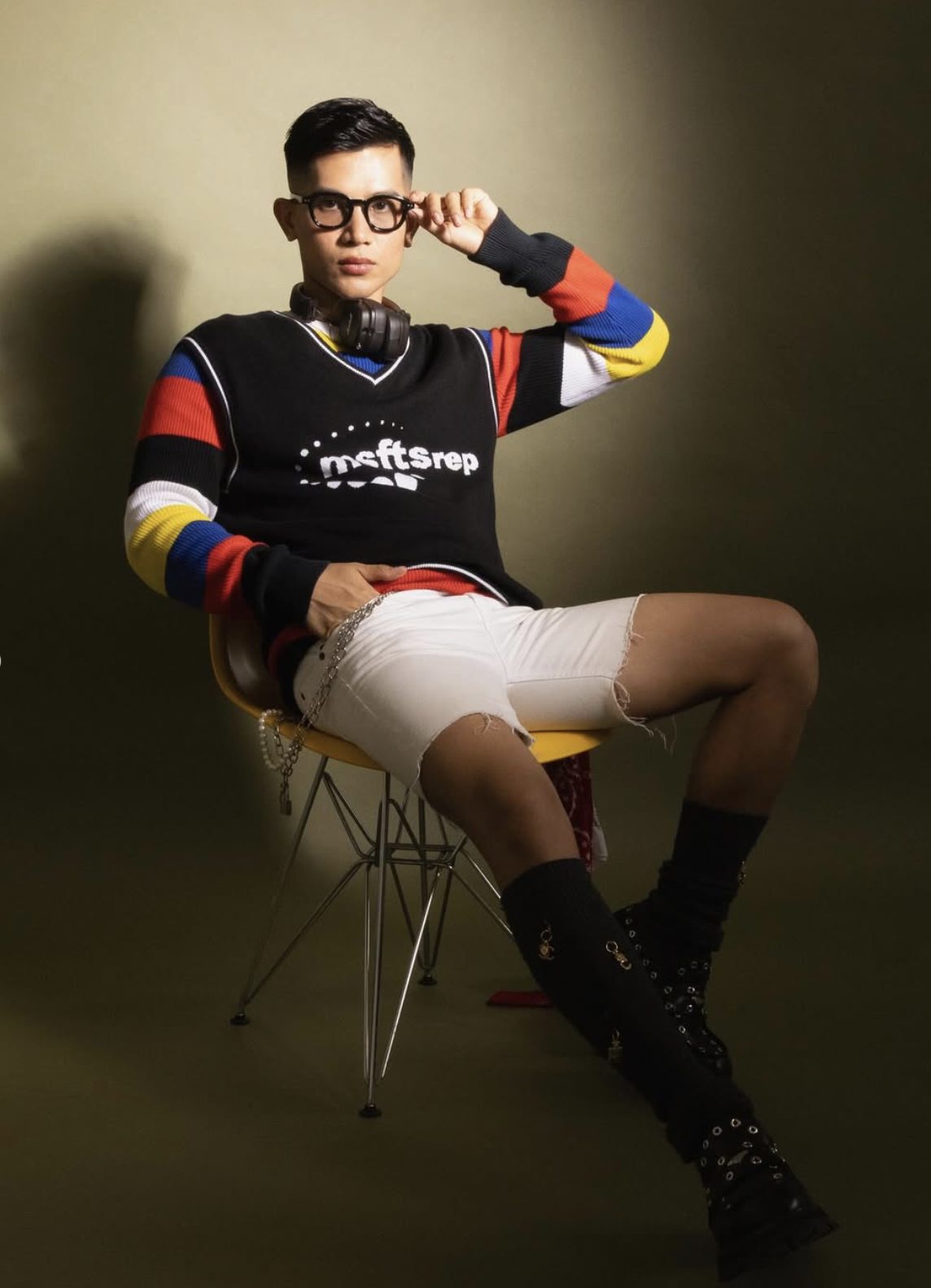 Young person sitting on a yellow chair against a green background. Creative studio details and prop setup inside The Space MCR, North Manchester.