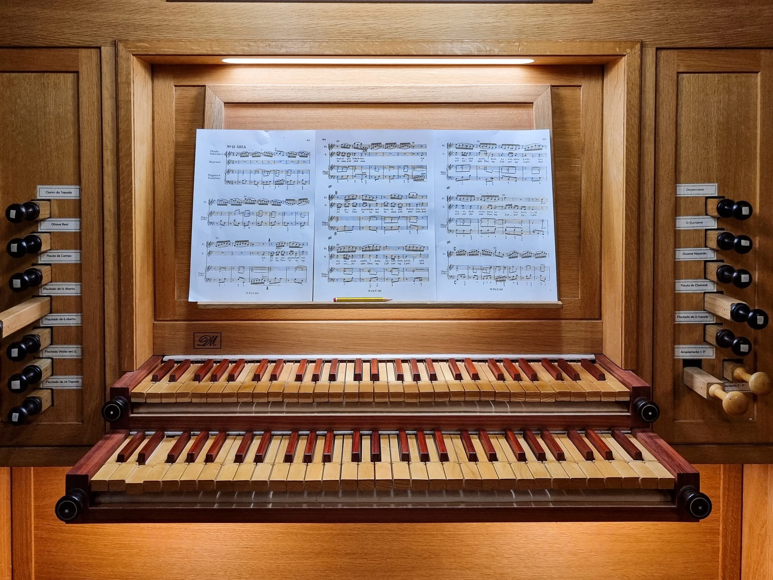 Picture of an organ's console showing two keyboards and a score on the shelve