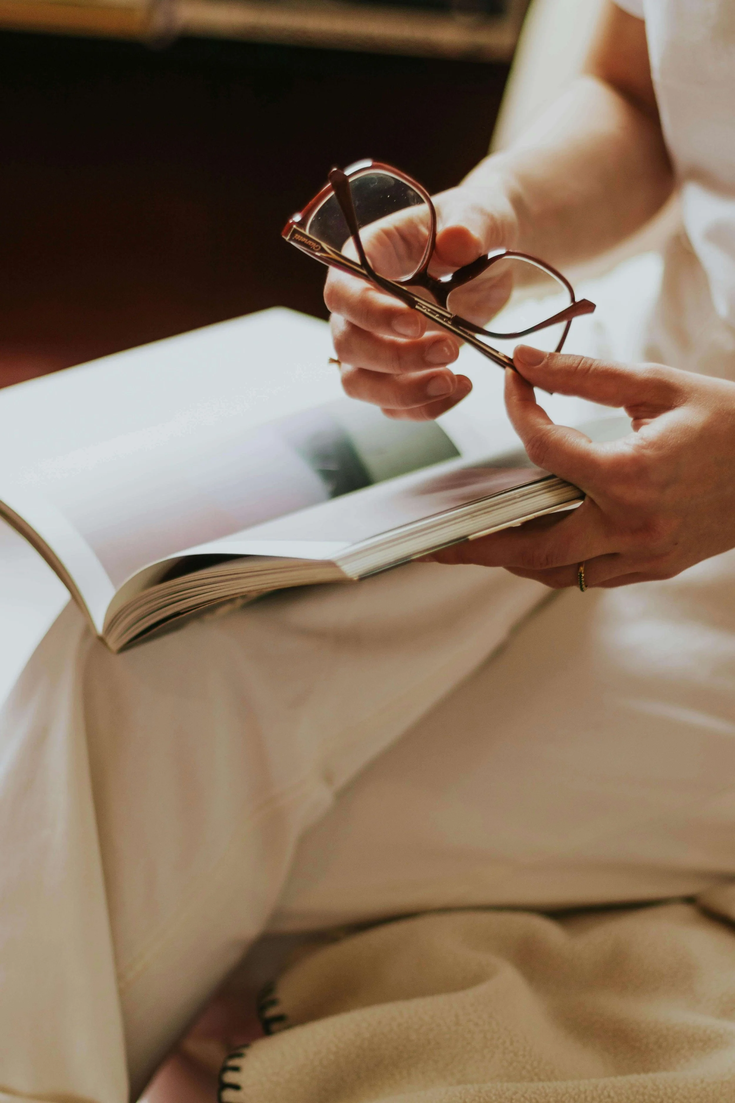 Person holding glasses and reading a book.