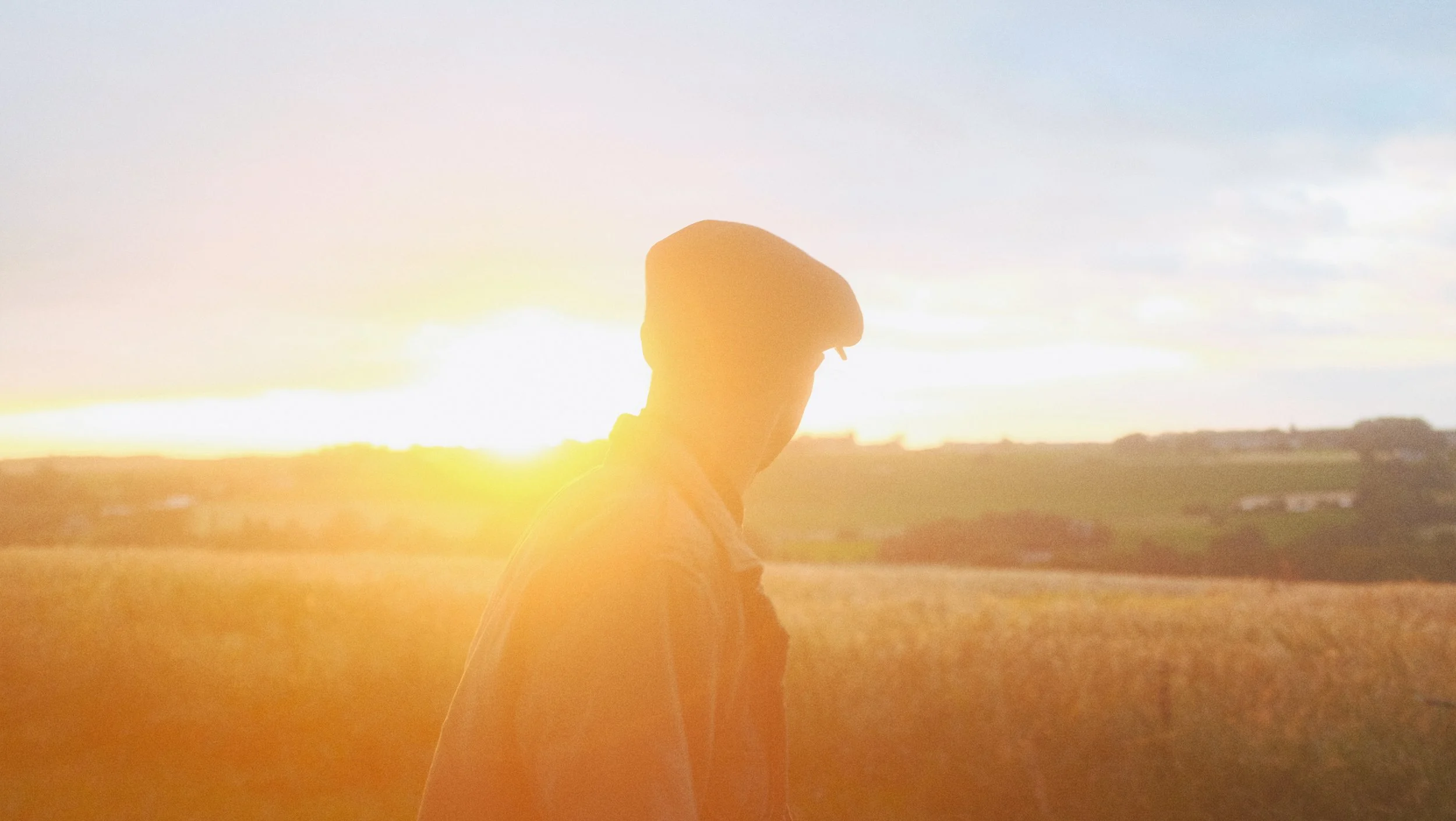 Silhouette d'une personne marchant dans un champ lors du coucher du soleil