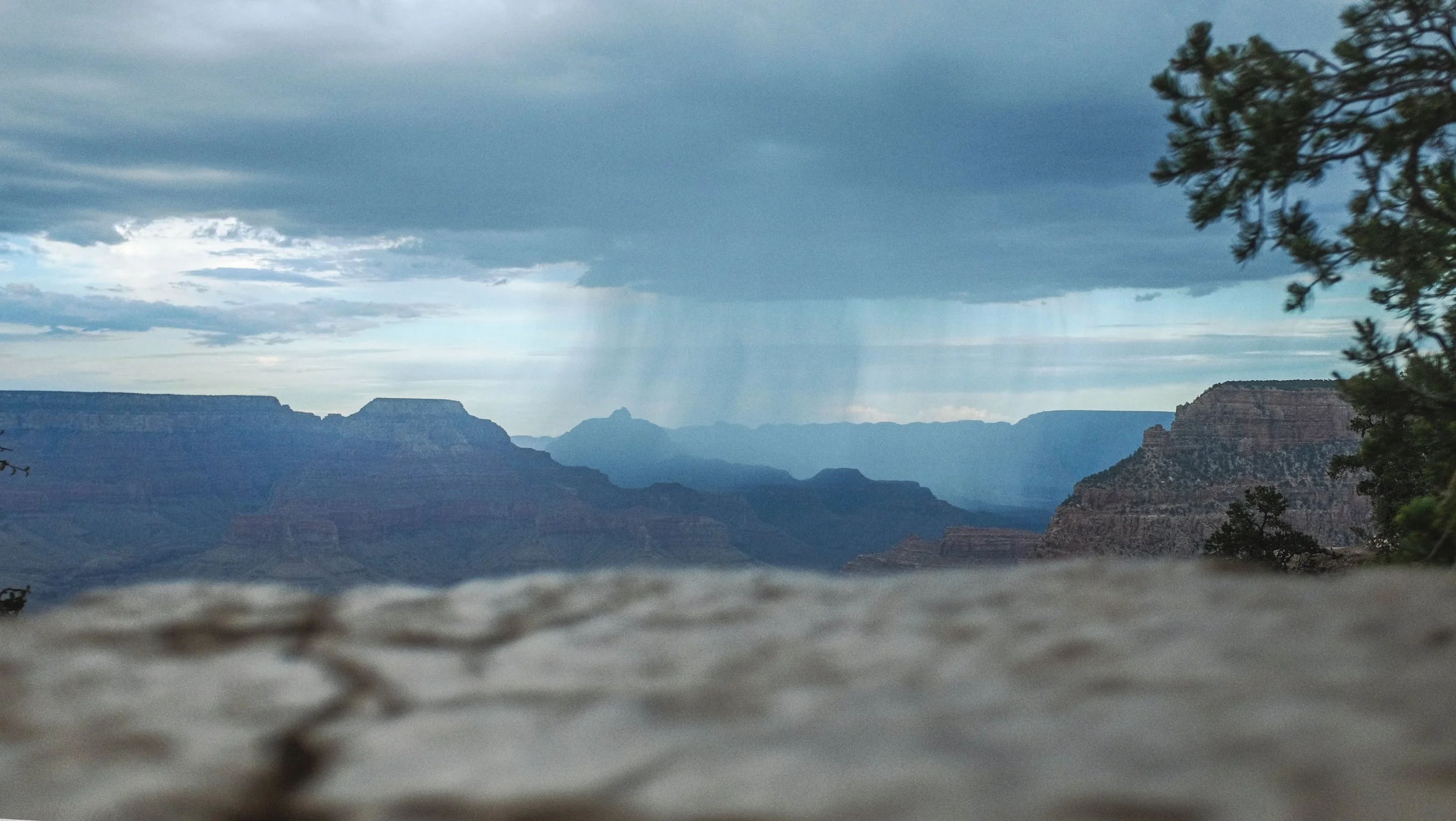 Vue du Grand Canyon avec des nuages sombres et de la pluie au loin.