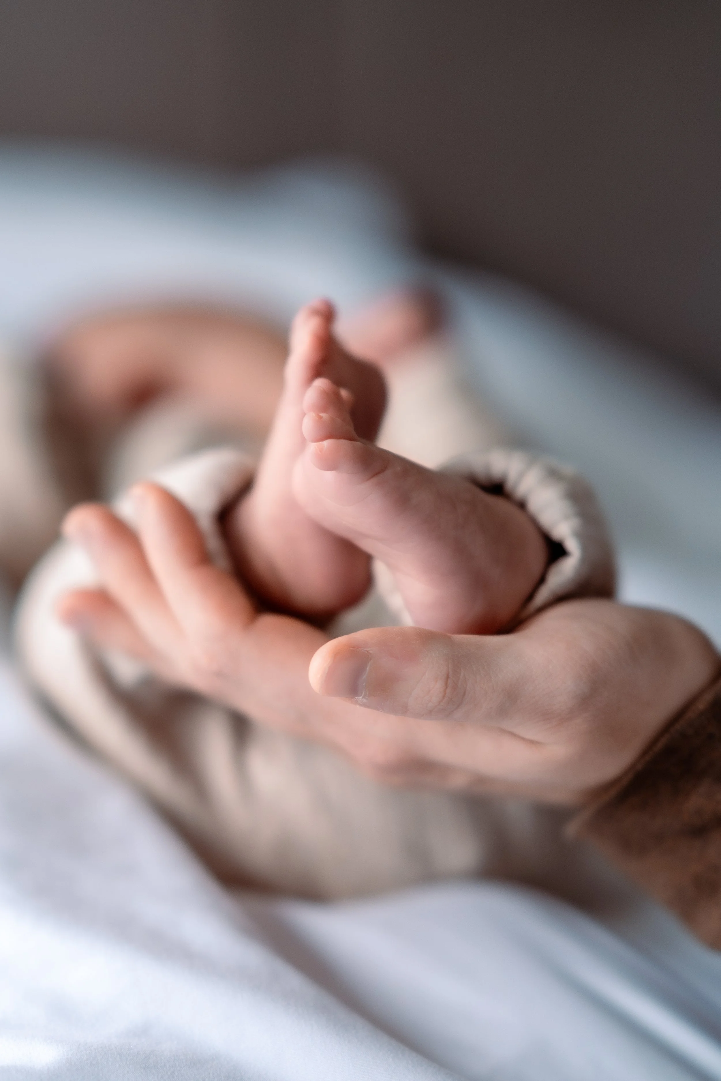 Close-up of an adult holding a newborn baby's tiny foot.