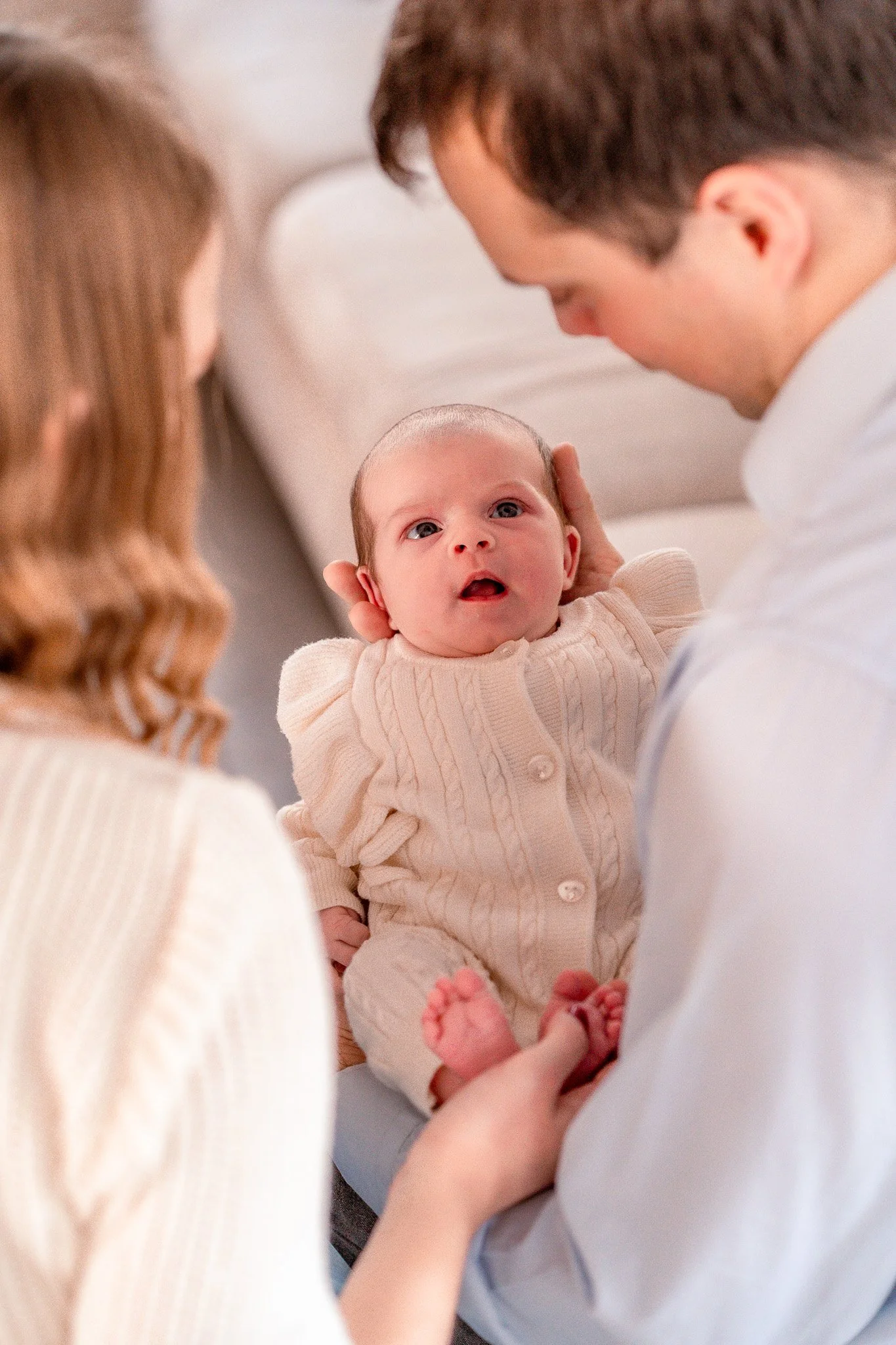A family holding a newborn baby in a bright, cozy room.