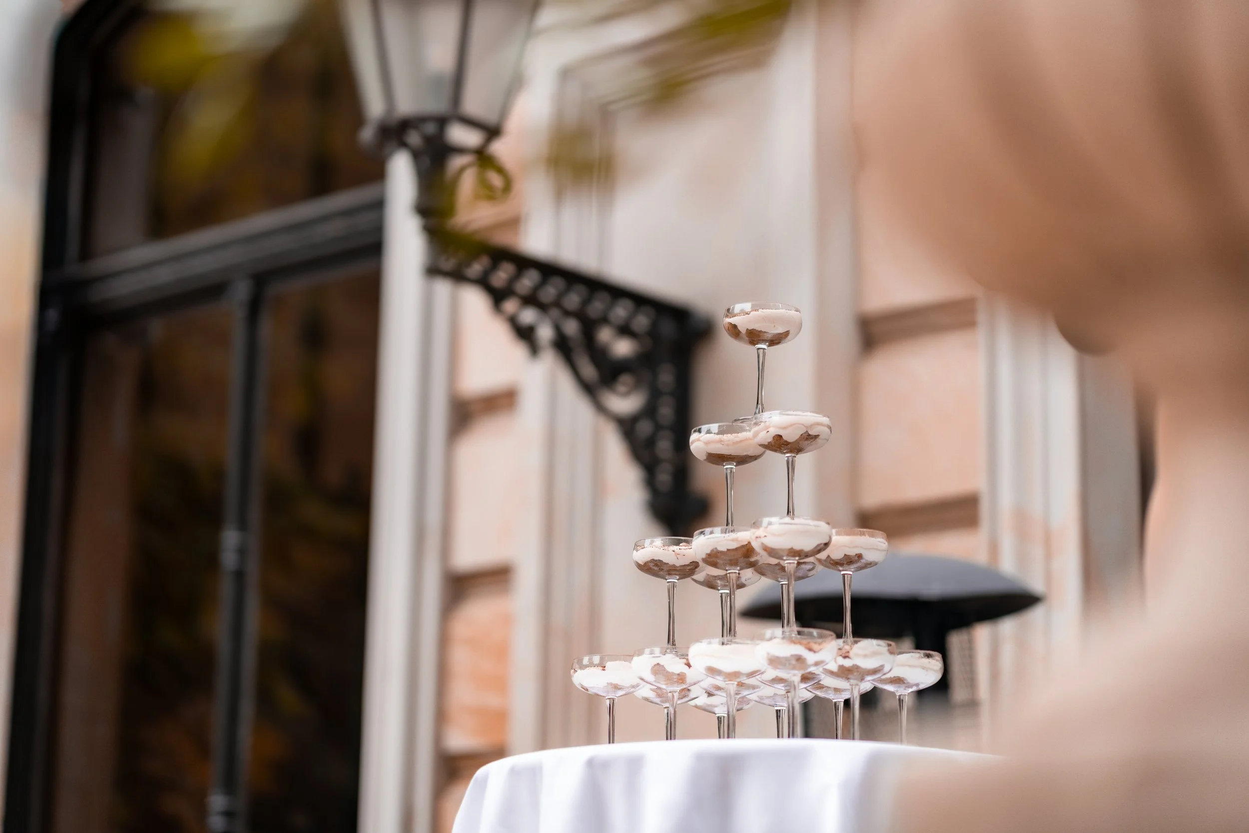 A tiered arrangement of chocolate and vanilla dessert glasses on a white tablecloth at an outdoor event.
