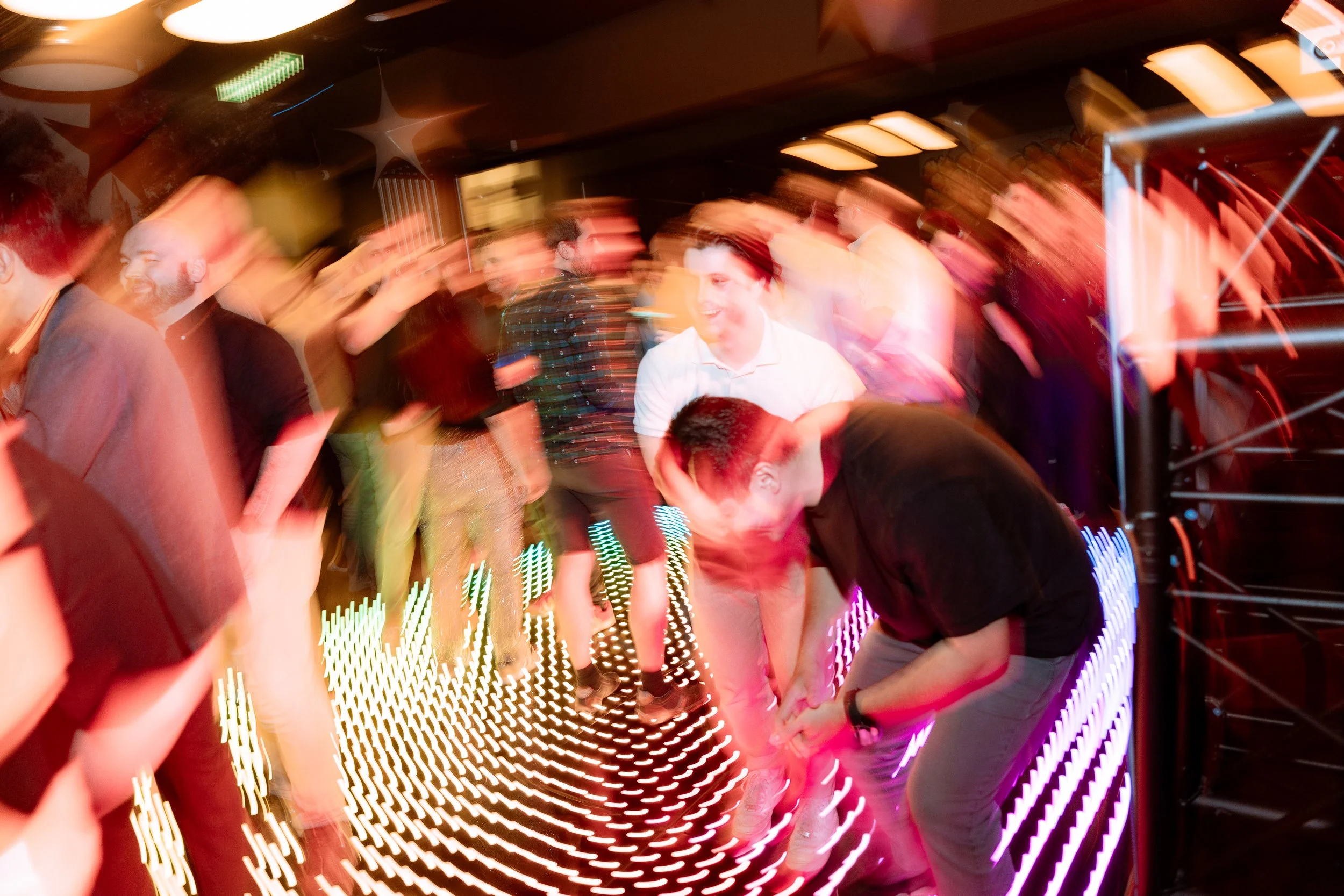People dancing at a party with colorful lights and blurred motion capturing movement and energy.