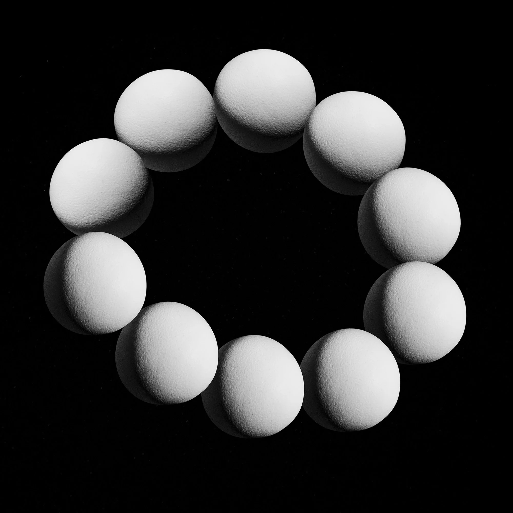 A circular arrangement of white textured spheres on a black background, forming a ring.