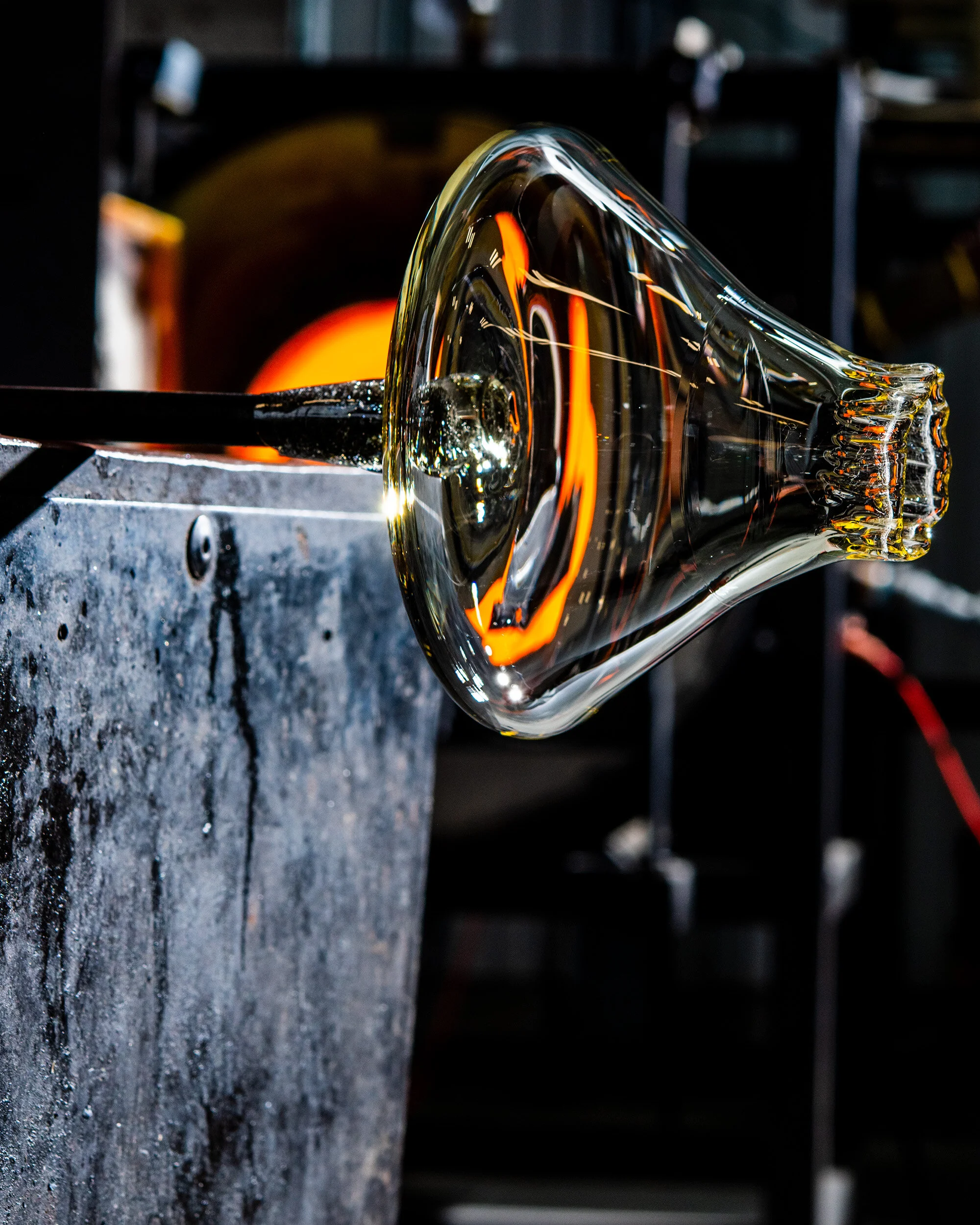 Glassblowing process, a glass object being shaped at a furnace.