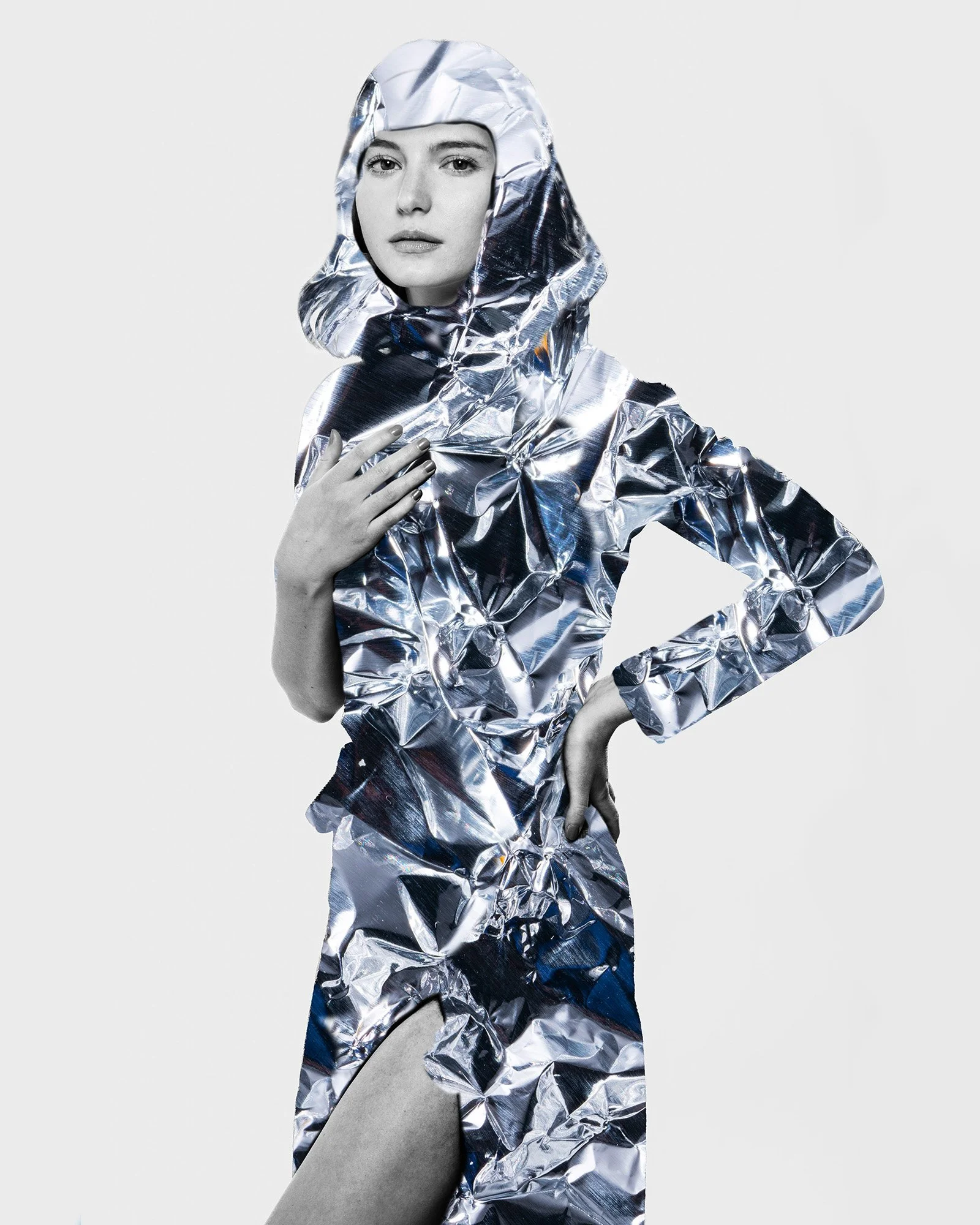 Woman wearing a shiny, crinkled silver outfit with a hood, posing against a plain background.