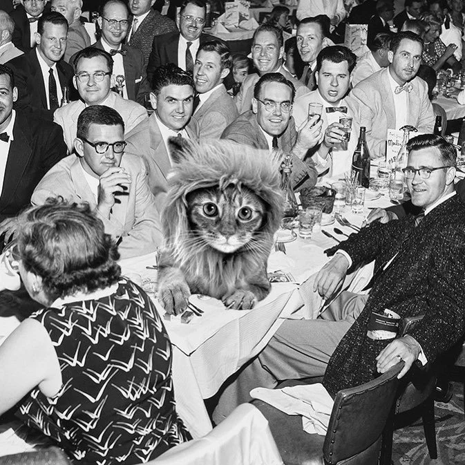 A group of men and women in vintage clothing gathered around a banquet table with drinks and food, with a lion with a human-like expression edited into the center of the table, replacing the body of an animal.
