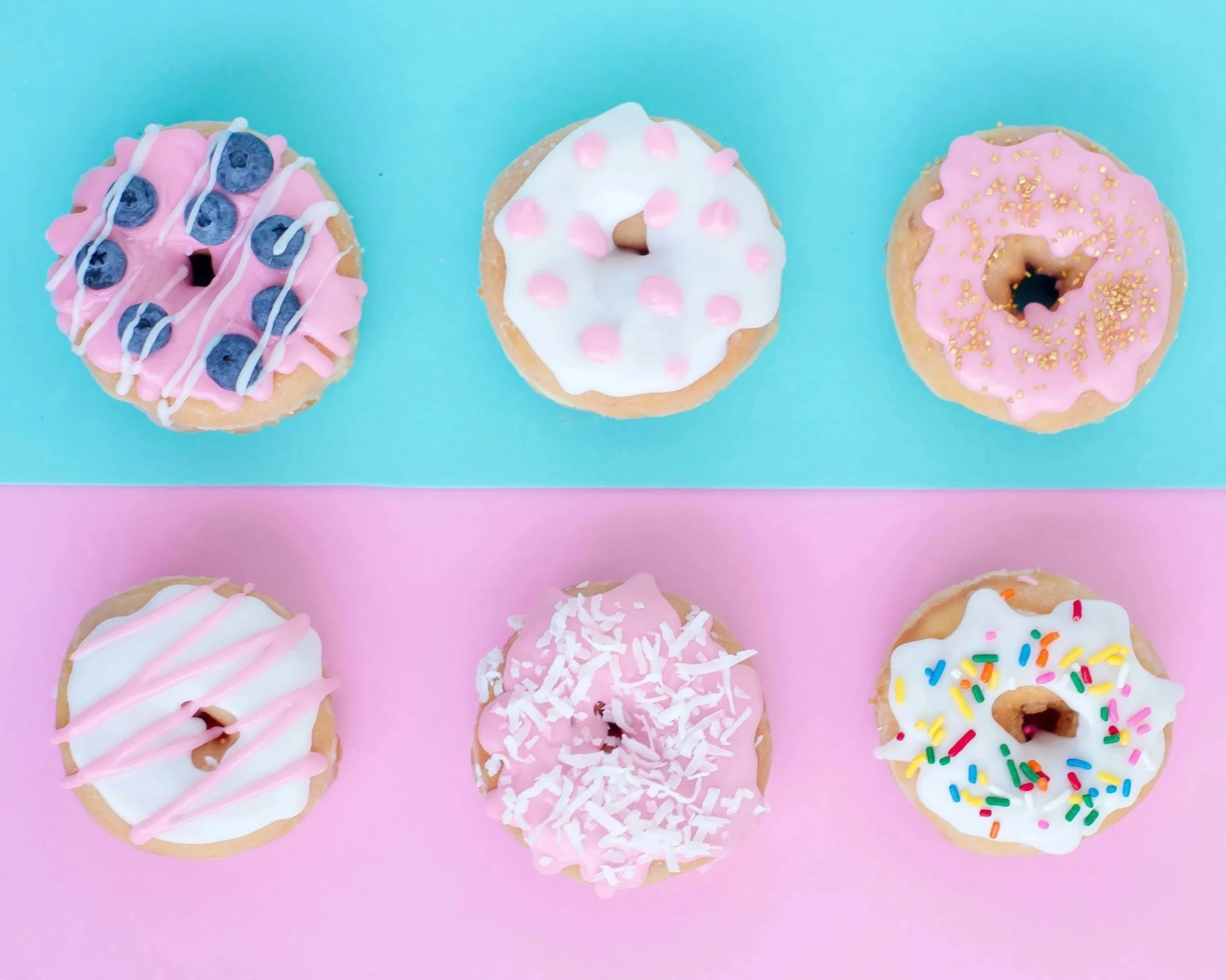 Six donuts decorated with pink, white, and colorful sprinkles, arranged in two rows on pink and blue backgrounds. Used as a visual marker for Cræft’s Specialist services.