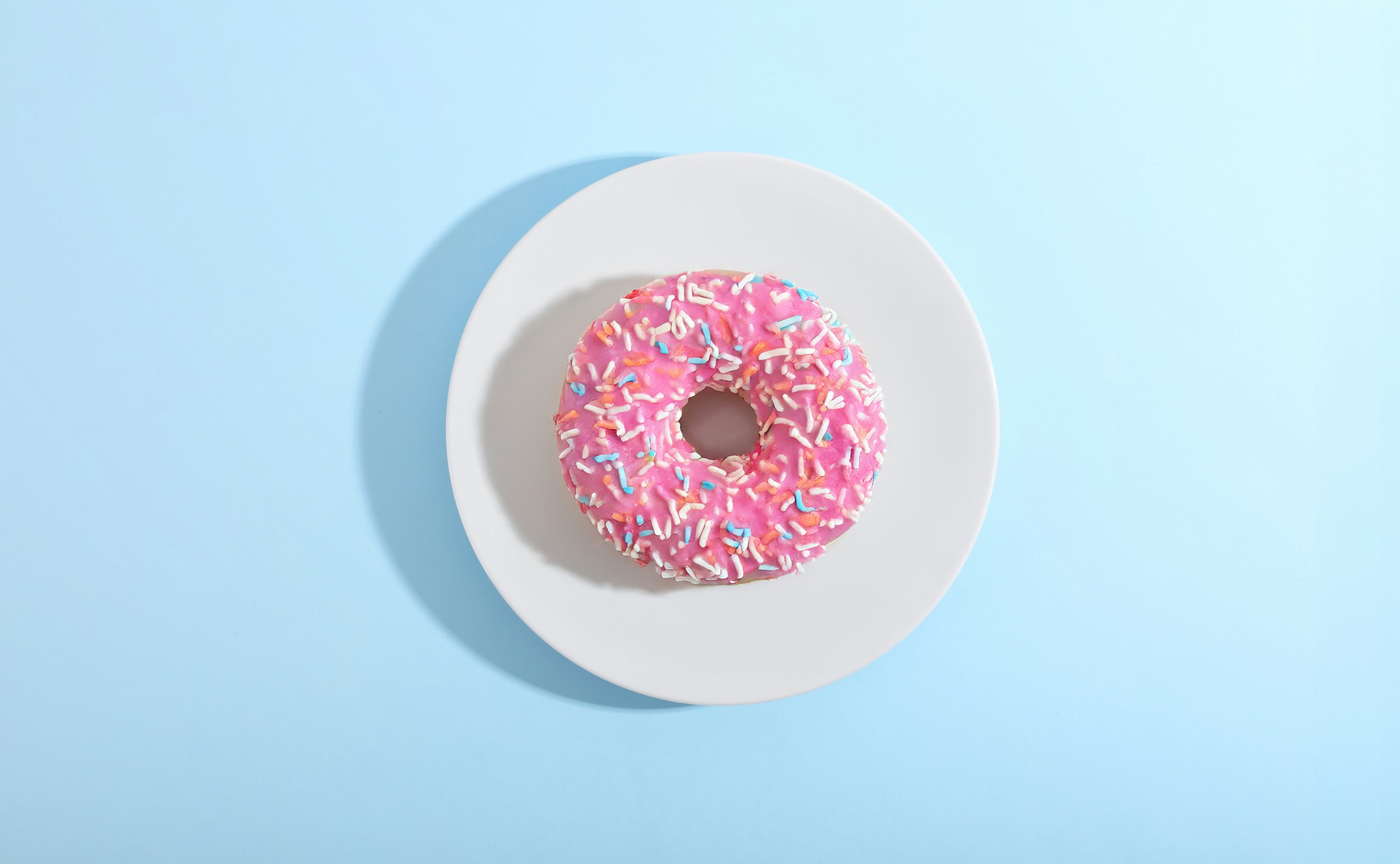 Pink doughnut on a white plate against a blue background, used to introduce Cræft’s brand leadership Core and Specialist Services.