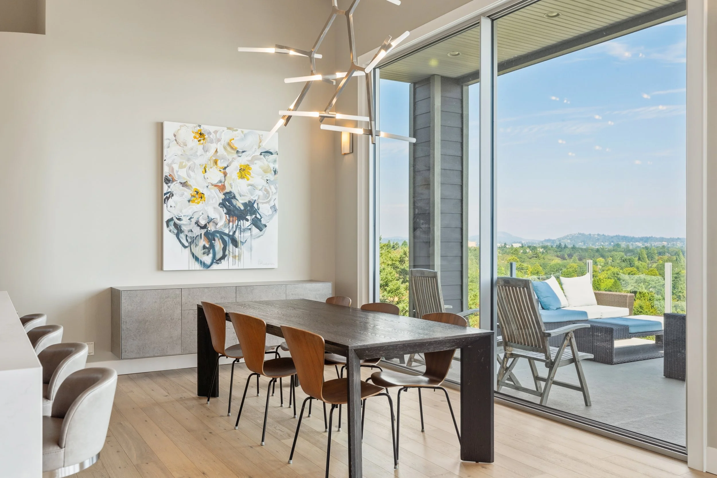 Modern dining room with large windows, outdoor patio, and scenic views