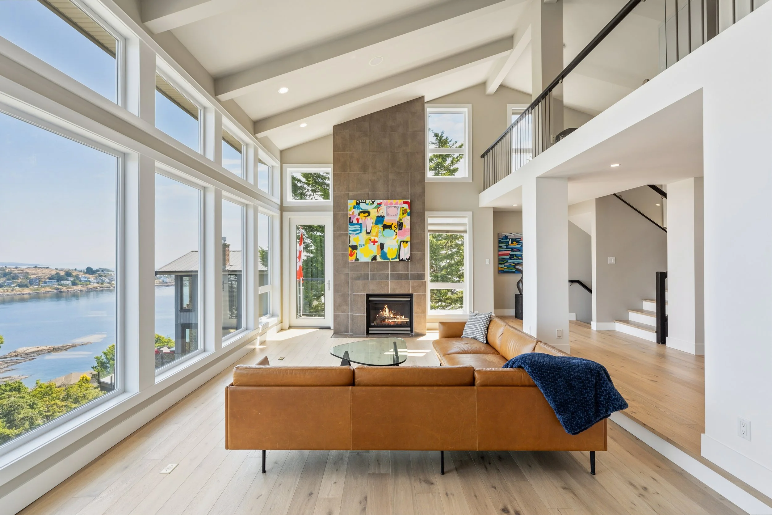 Bright modern living room with floor-to-ceiling windows, fireplace, and ocean views