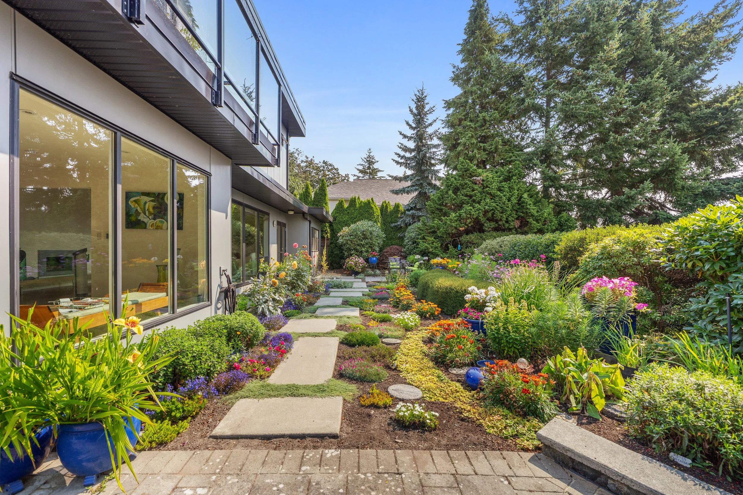 Landscaped garden beside a modern home with colorful flowers and large windows