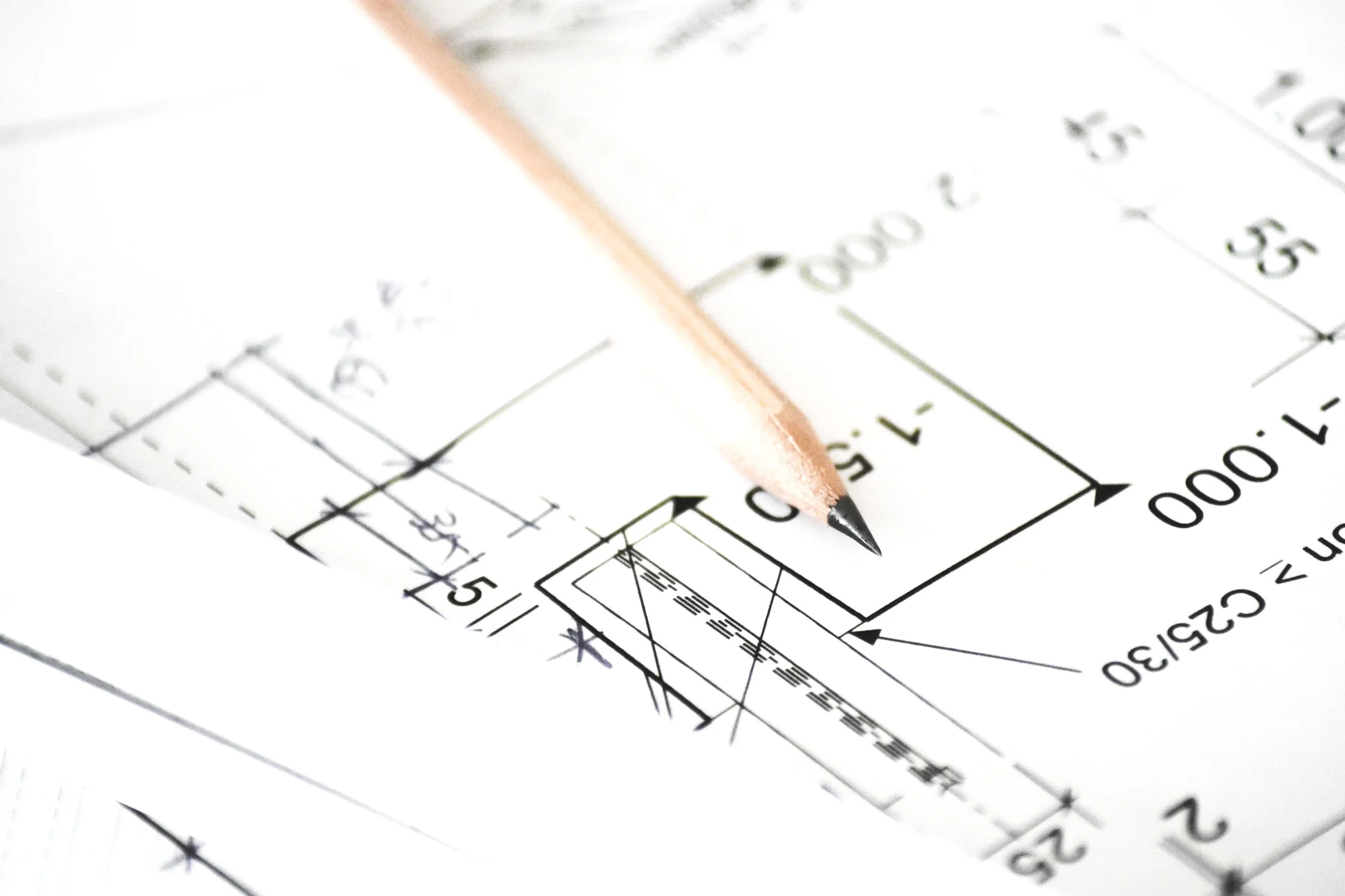 Close-up of an architectural blueprint with a pink pencil pointing at a specific area.